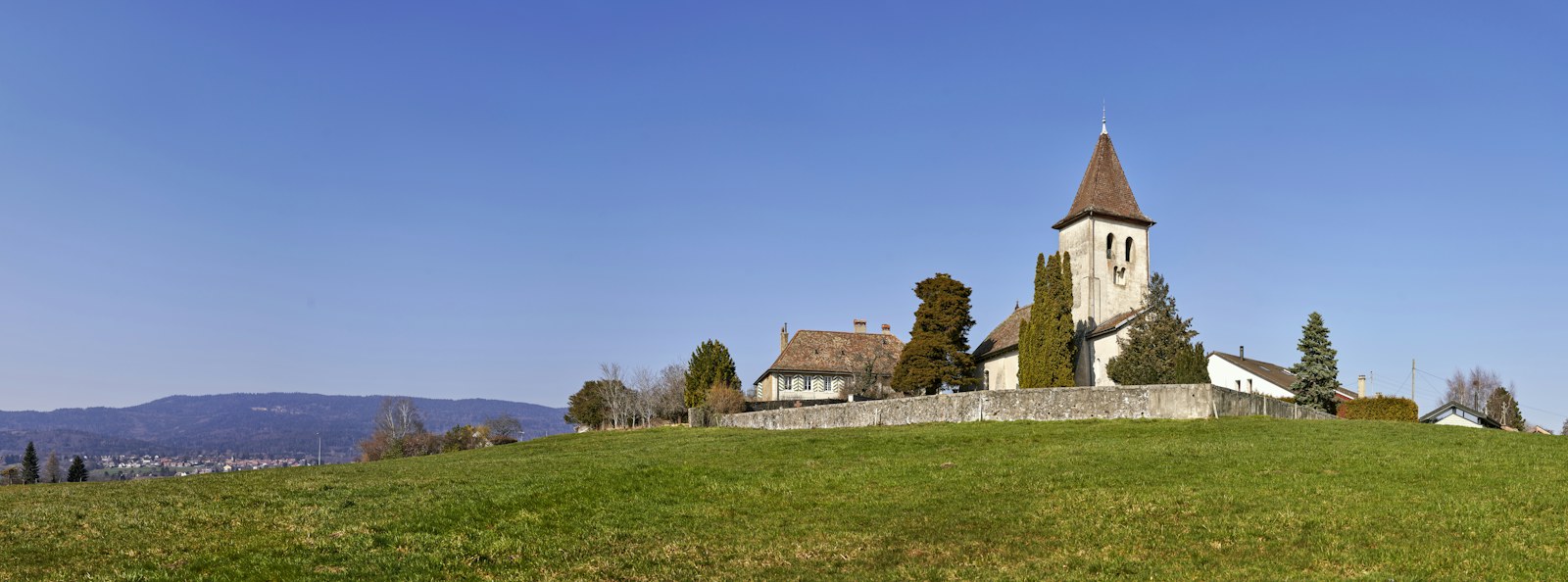 brown and white concrete house near green grass field under blue sky during daytime
