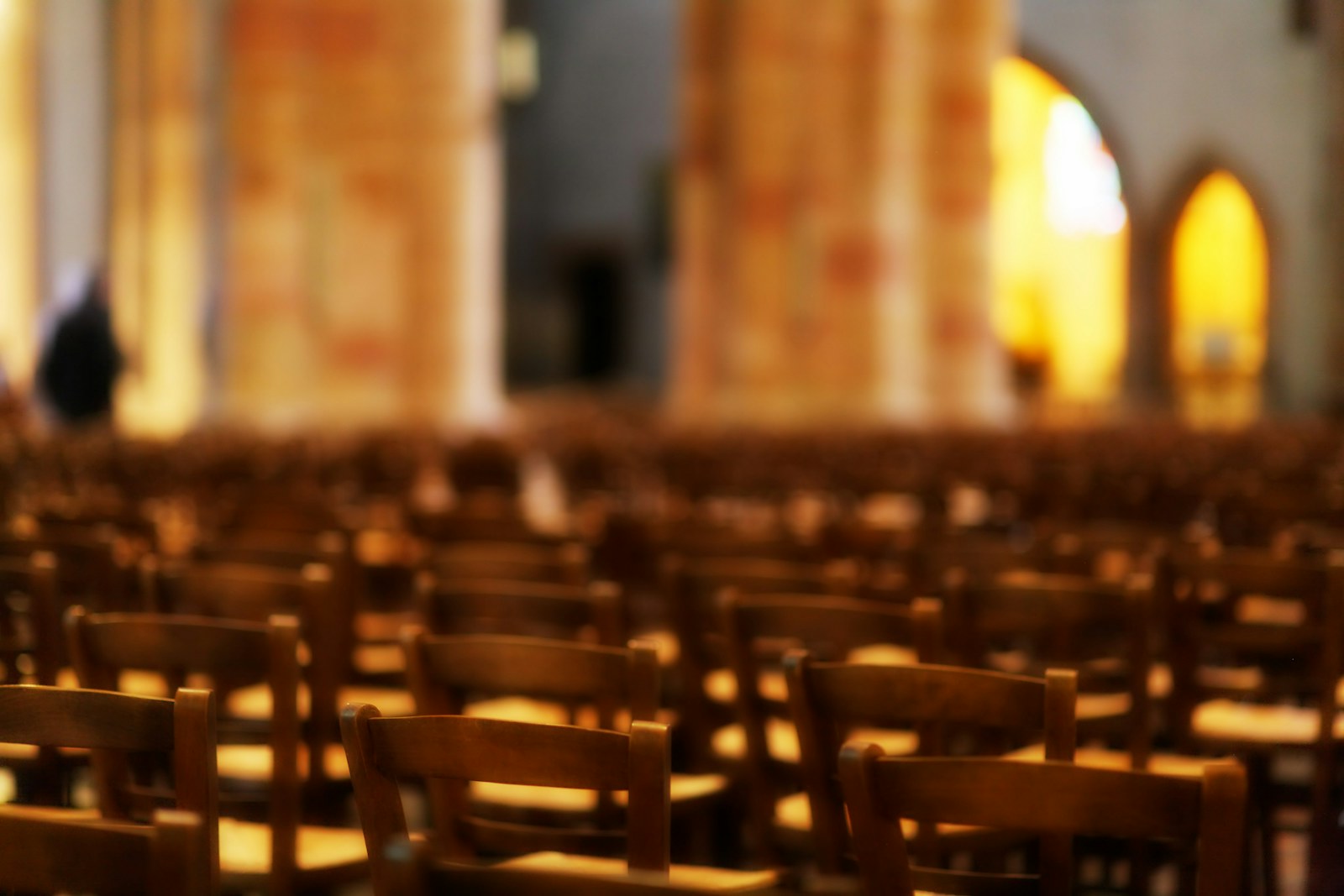 Rows of empty wooden chairs in a large hall