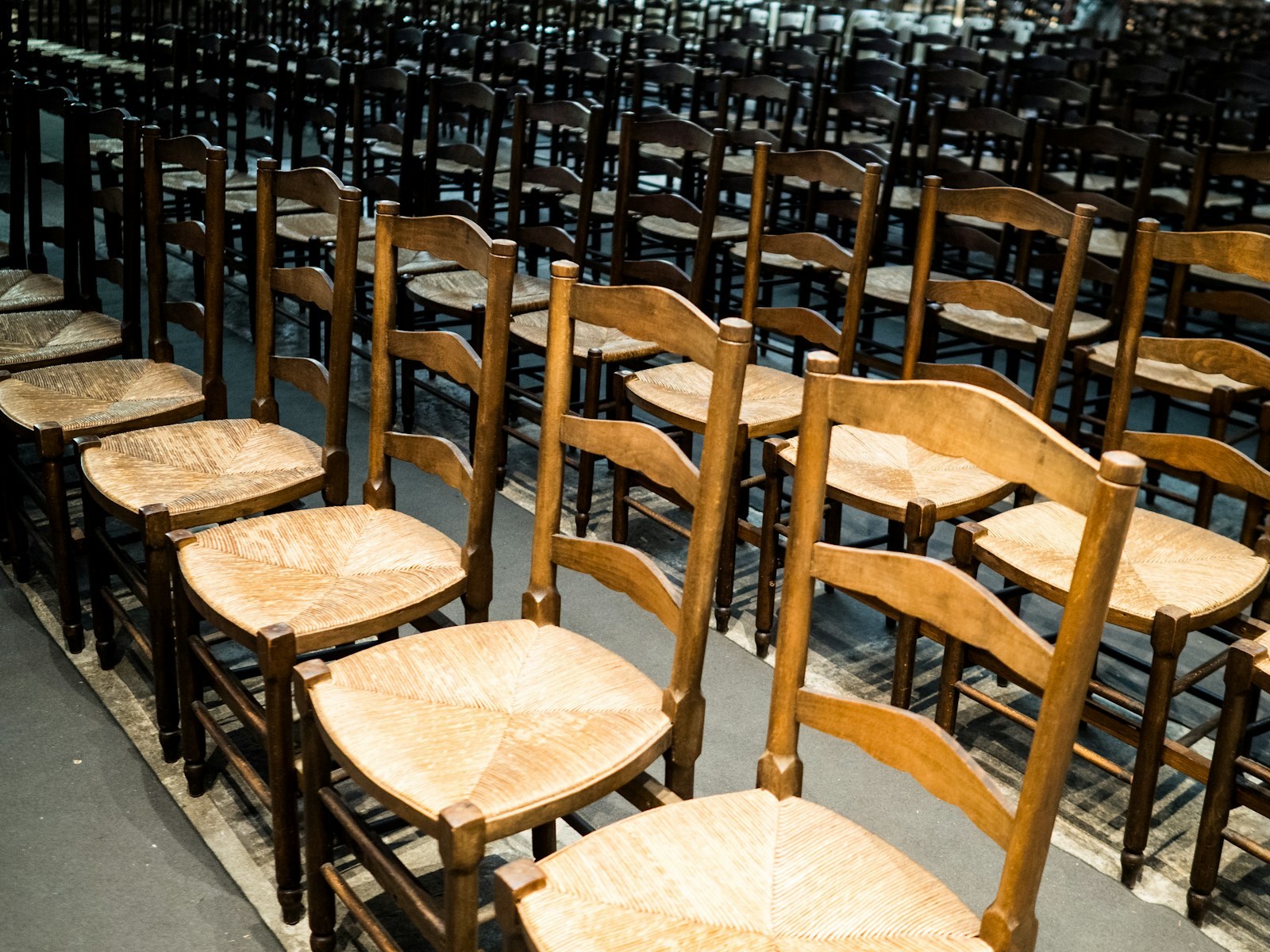 Rows of empty wooden chairs with woven seats