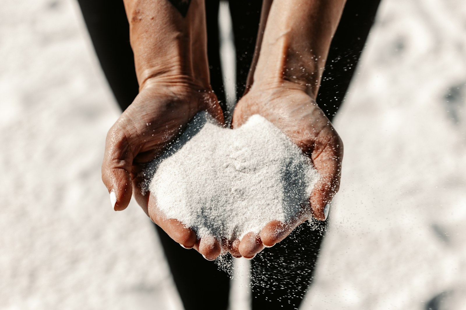 Hands holding white sand with sunlight
