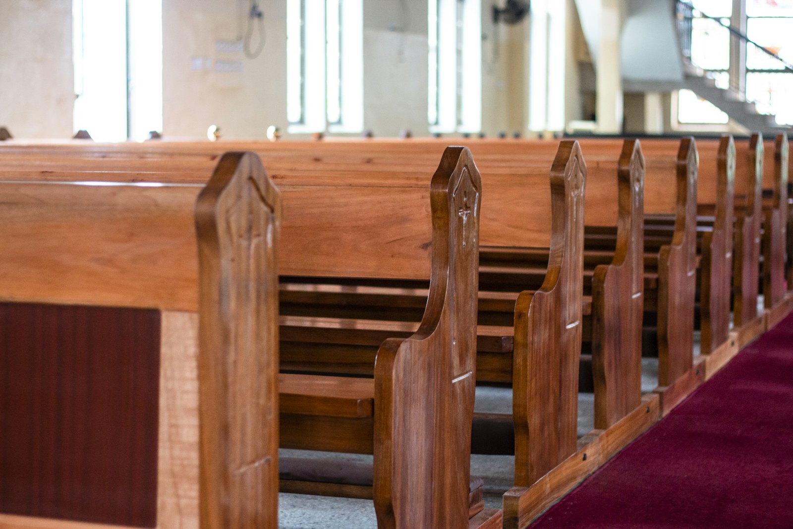 Wooden pews in a church with a red carpet