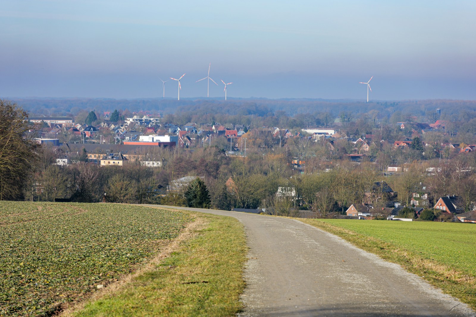 A winding road leads to a distant town with windmills