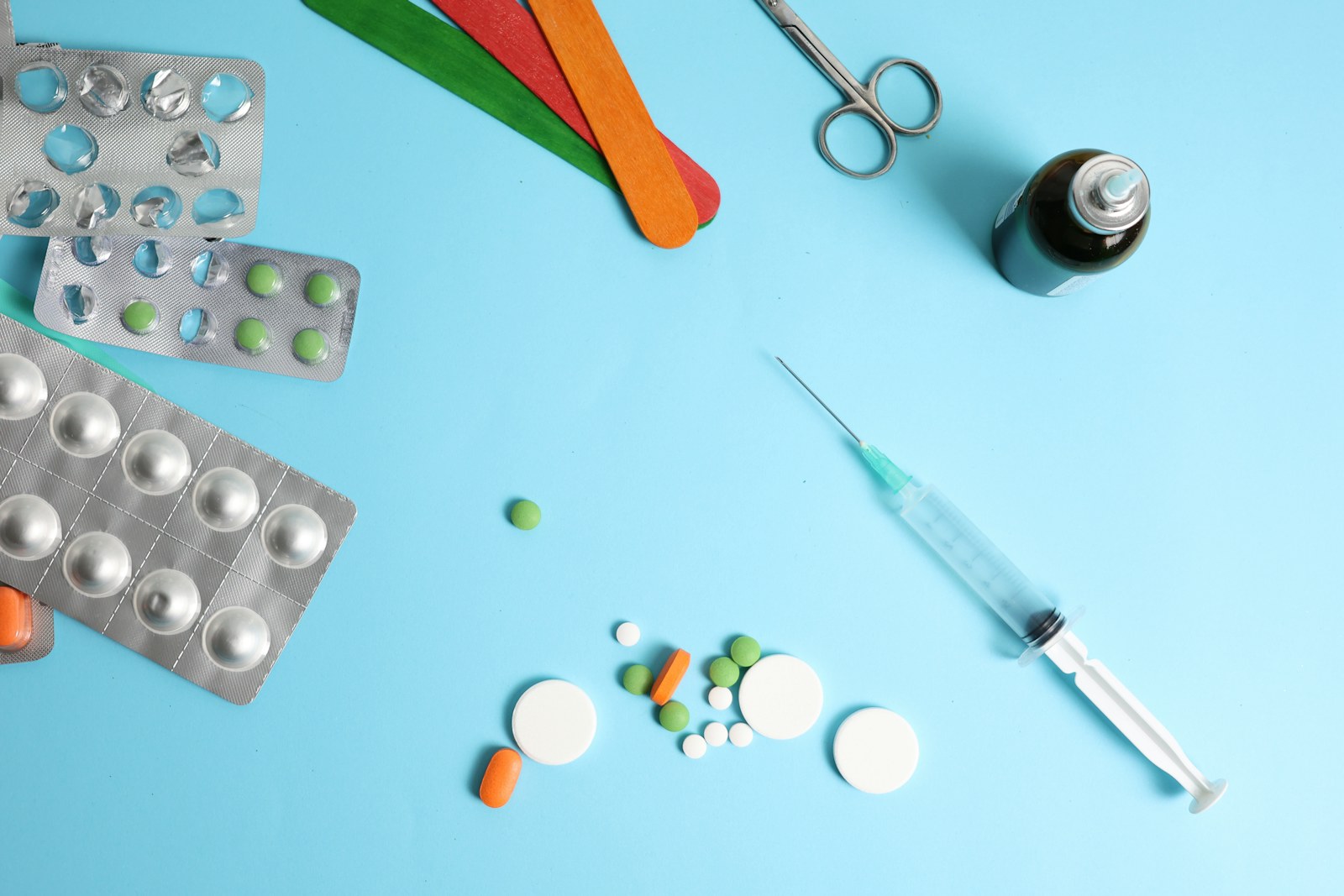 Medical supplies including pills, syringe, and scissors on blue