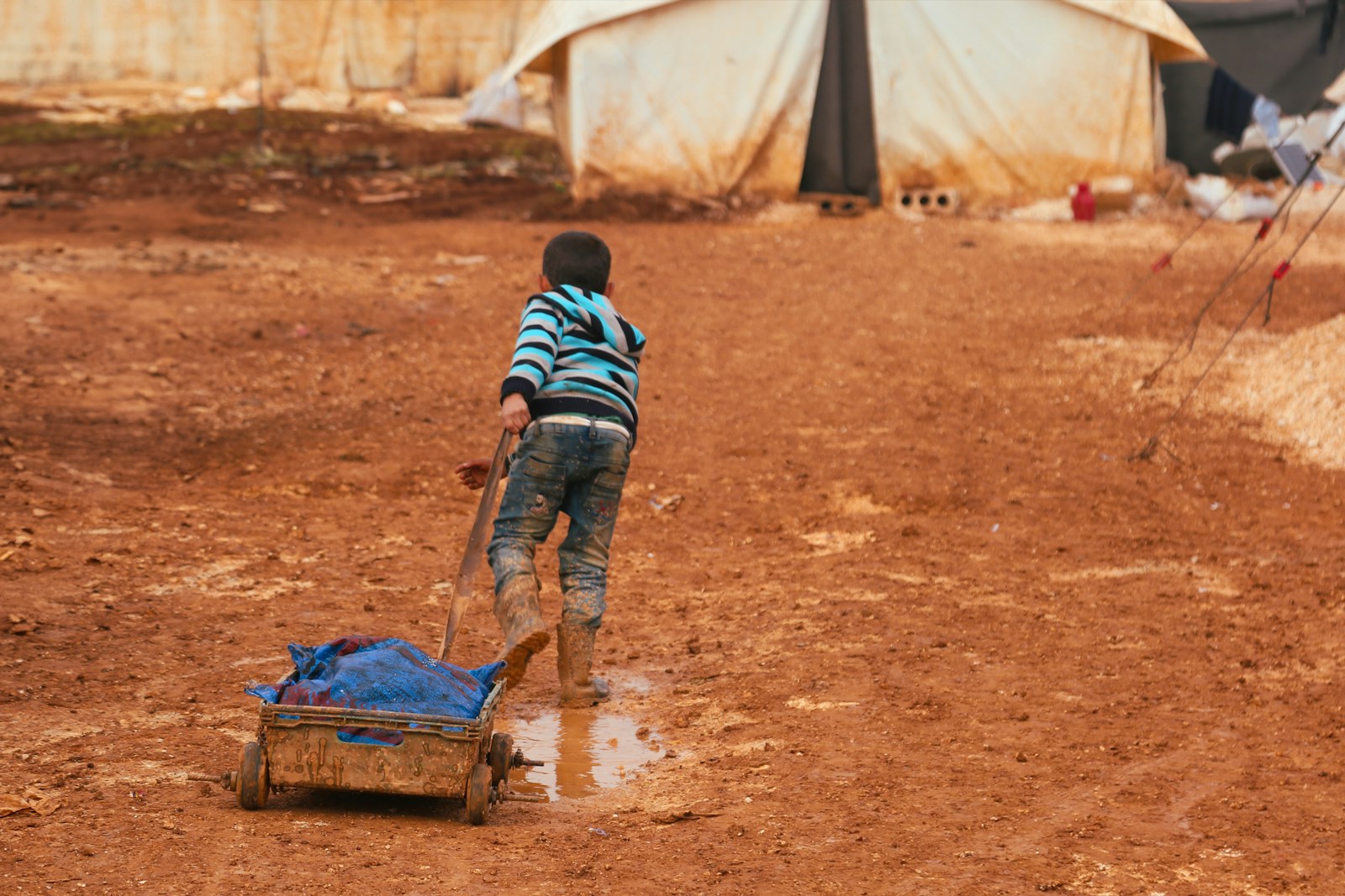 A young boy playing with a toy truck in a dirt field
