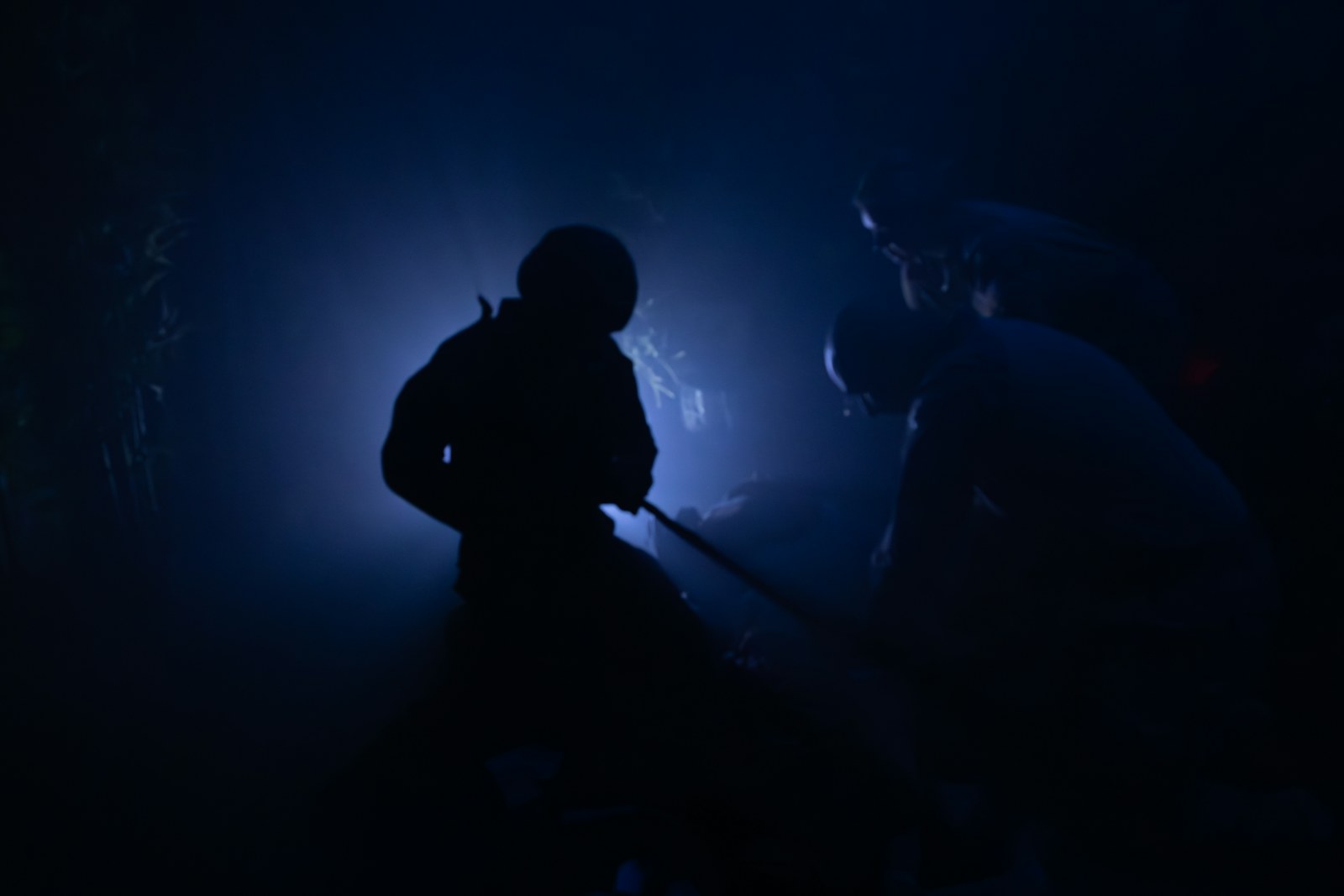 Two silhouetted figures in a dark, foggy environment