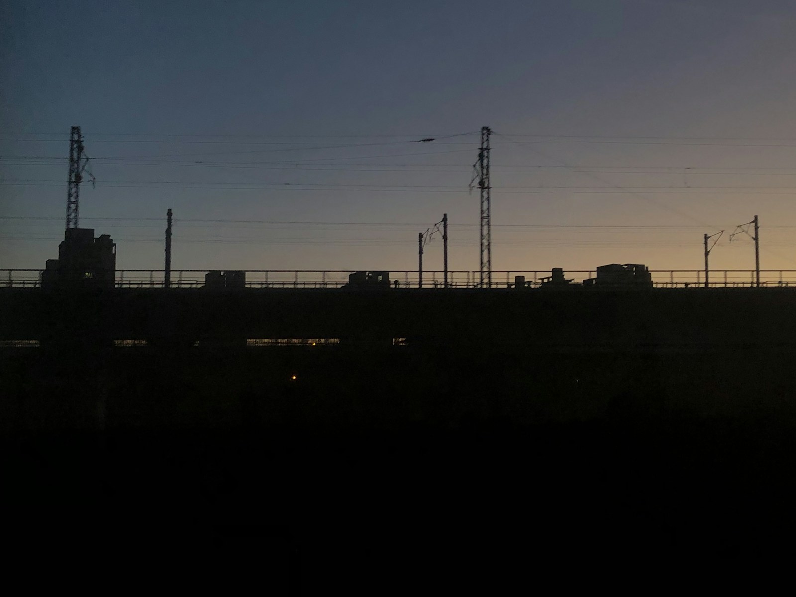 The sun is setting behind a fence with a city in the background