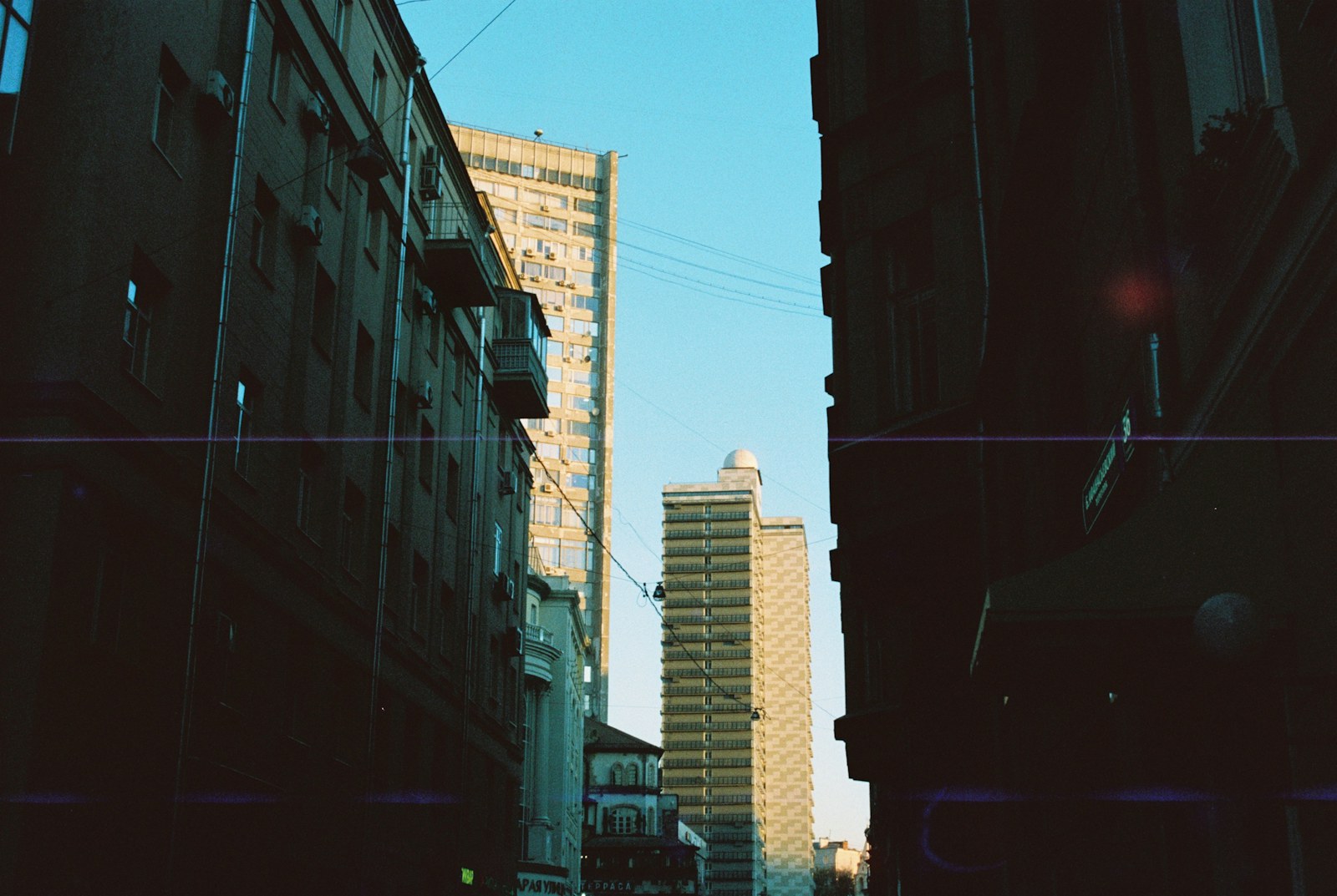 Sunlight illuminates distant skyscrapers framed by dark city buildings