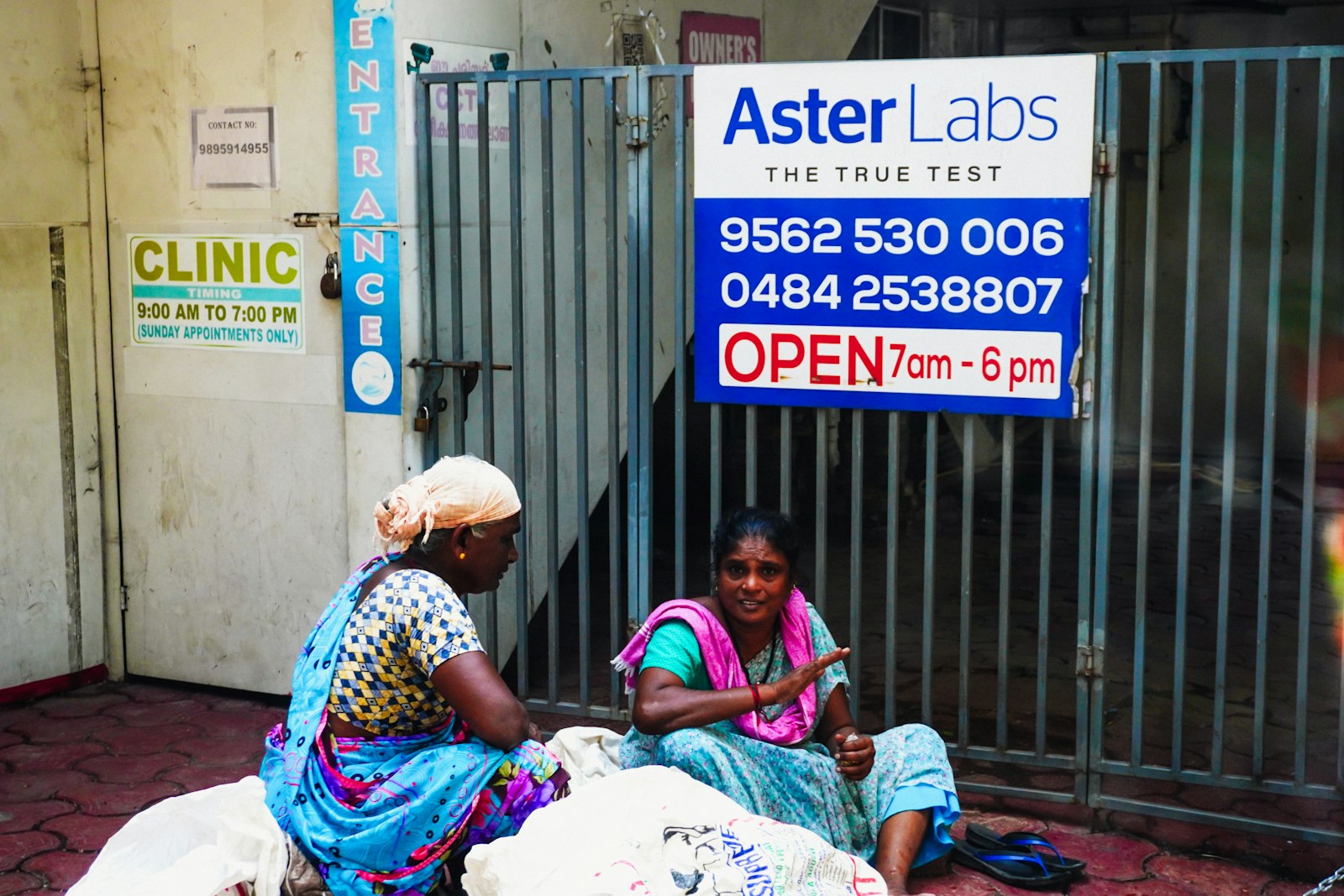 Two women sitting outside a clinic entrance