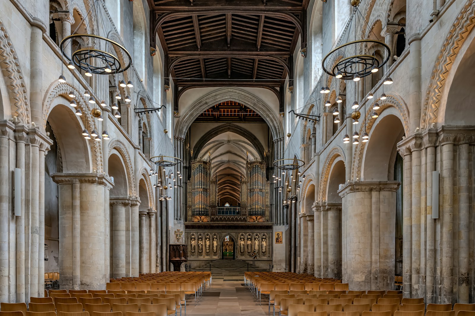 Rows of wooden chairs in the nave of a stone cathedral with arched columns