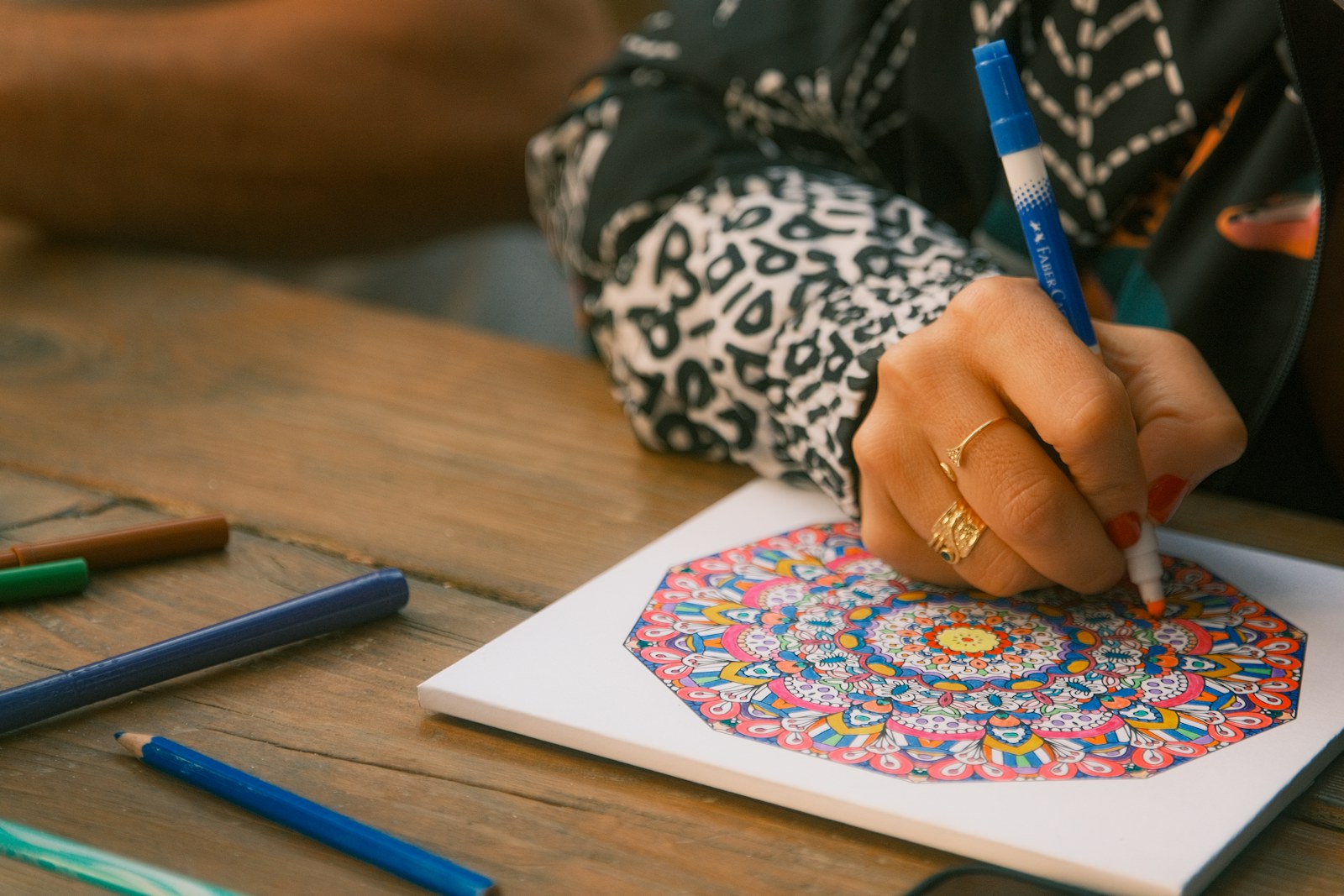 Person coloring a mandala with markers on paper