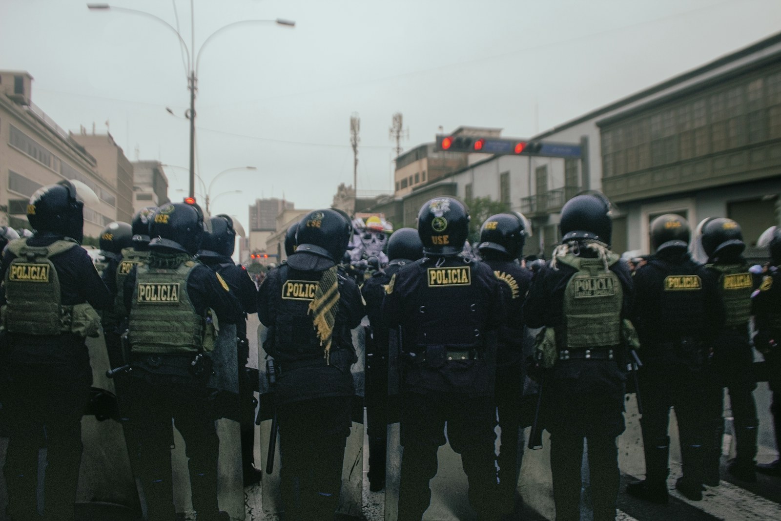 Police officers in riot gear stand on a street