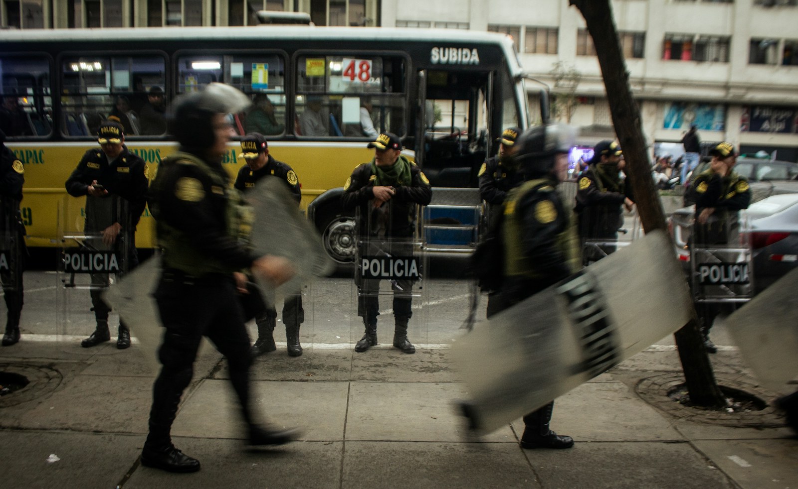 Police officers in riot gear stand on street