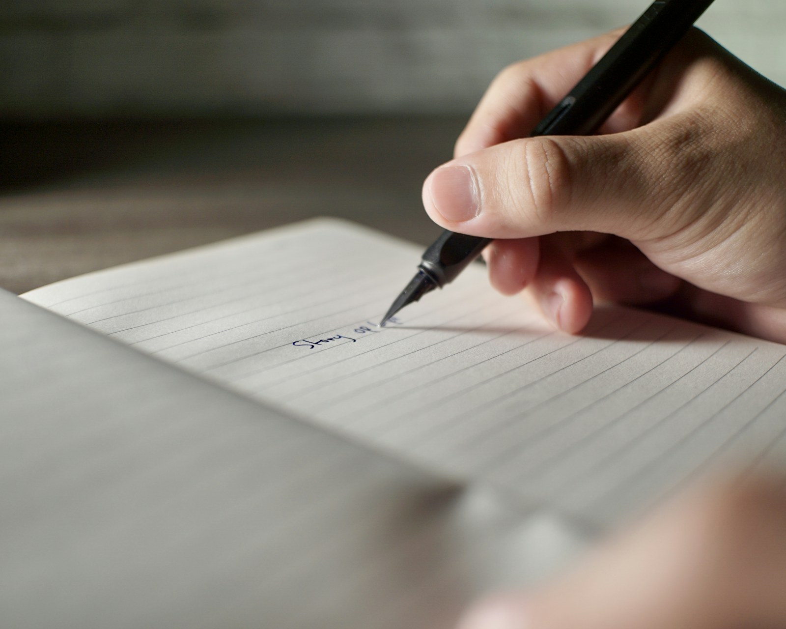 a person writing on a piece of paper with a pen