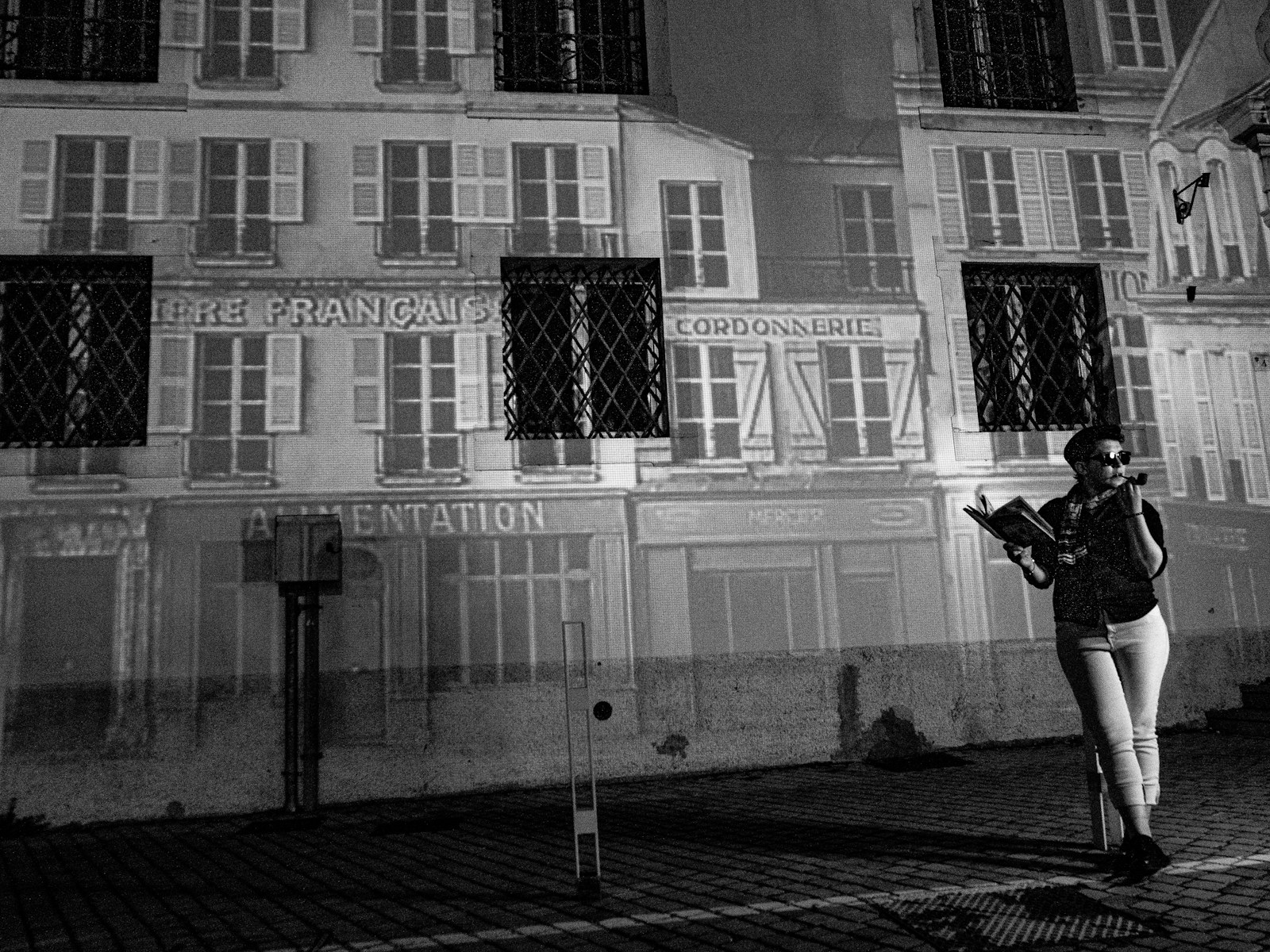 Woman reading on a scooter in front of a building