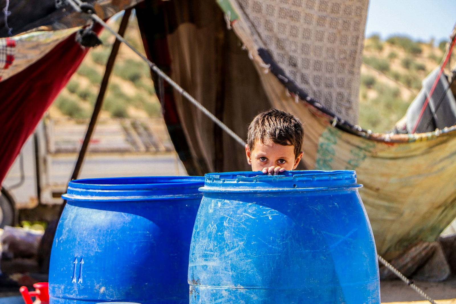A little boy sitting in a big blue pot