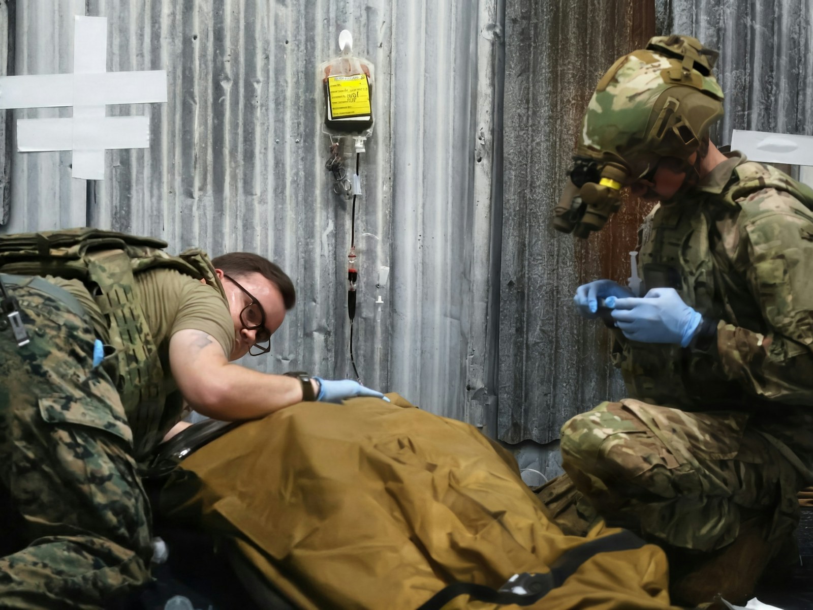Two military personnel providing medical care to a patient