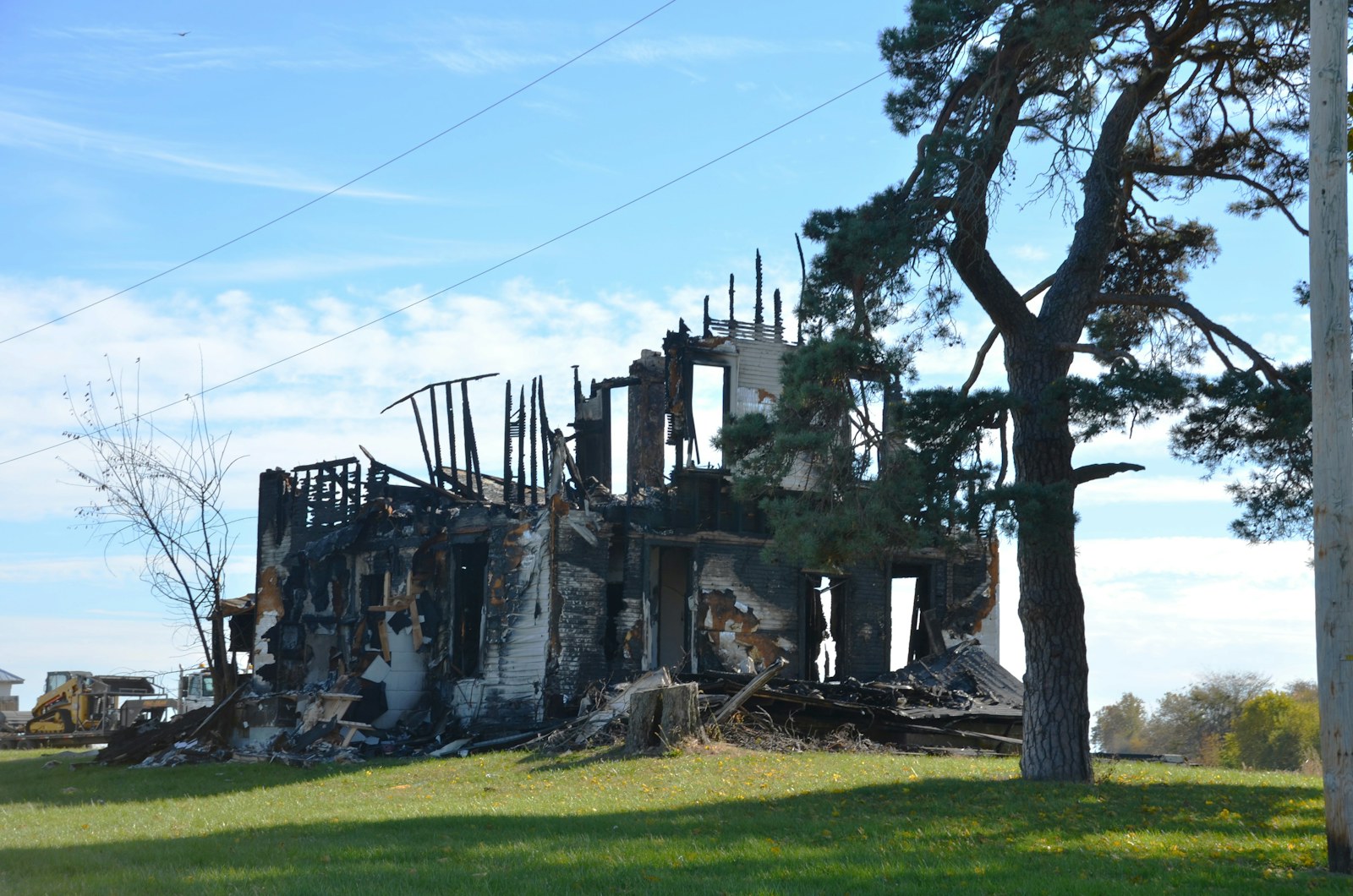 Burnt-out house with charred remains and a tree