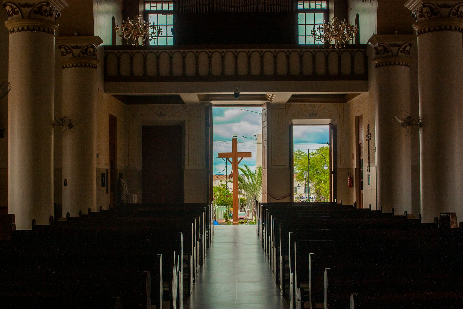 Empty church pews lead to a cross in the distance
