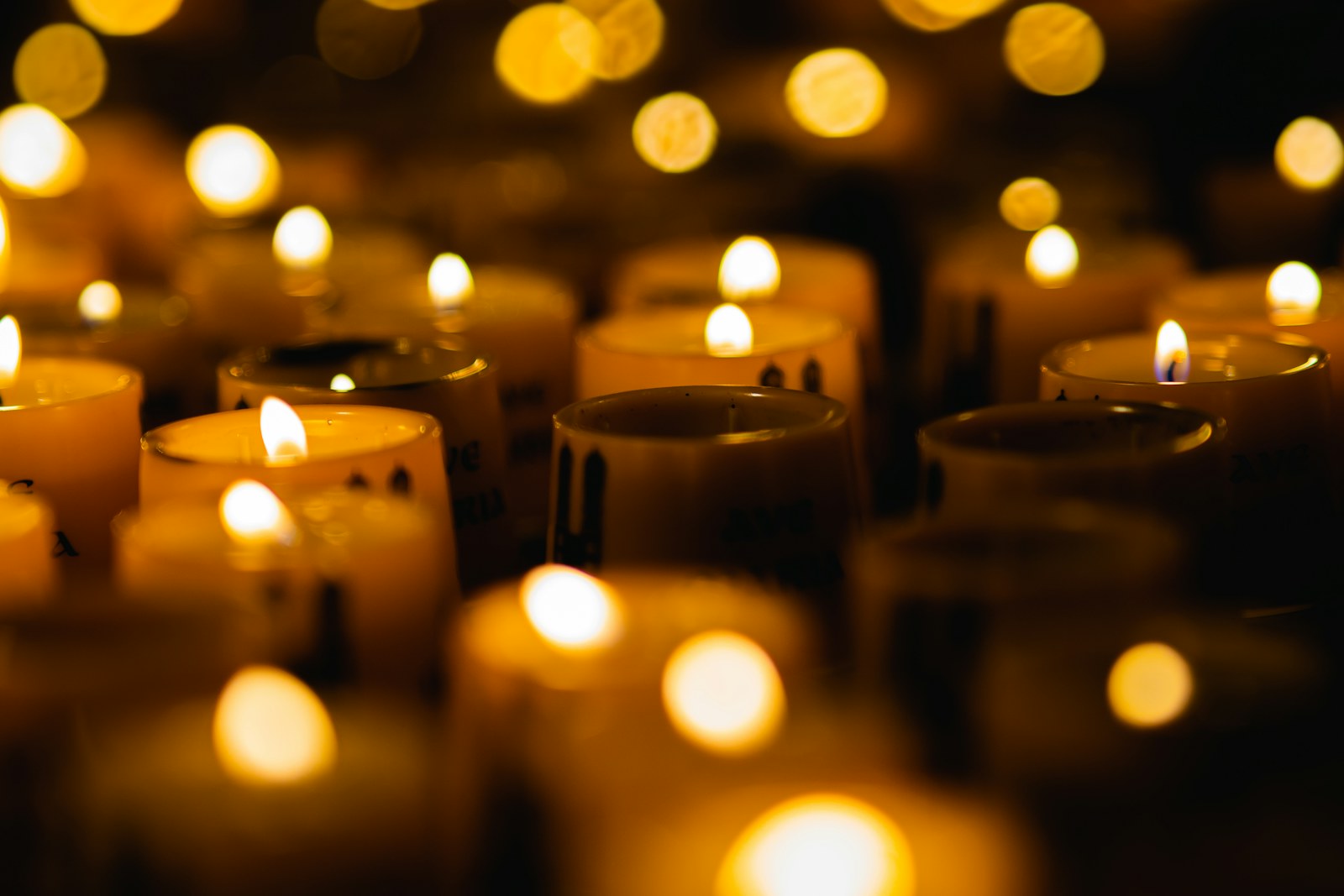 Rows of lit candles in a dark room