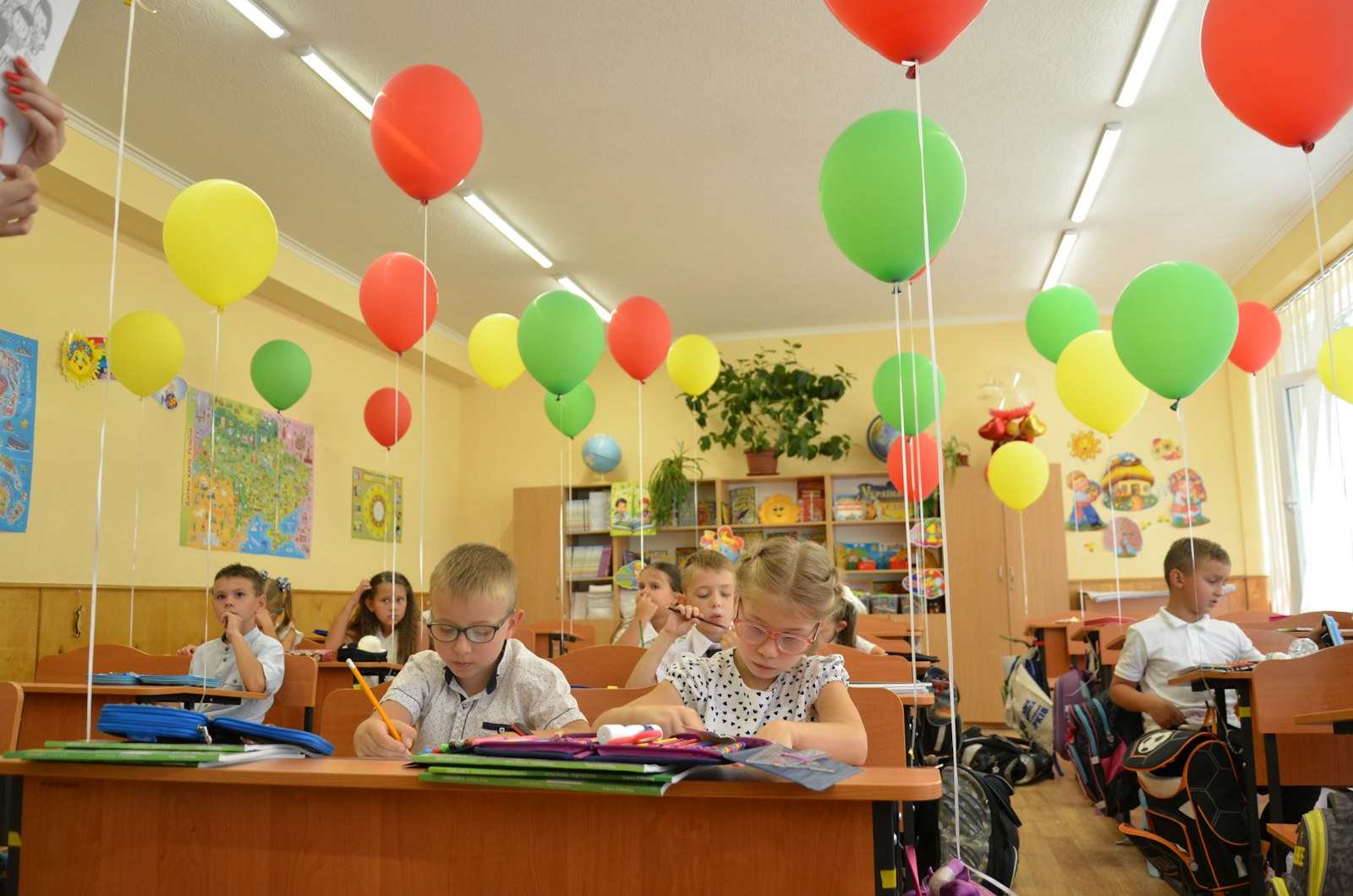 Children learning in a classroom decorated with colorful balloons