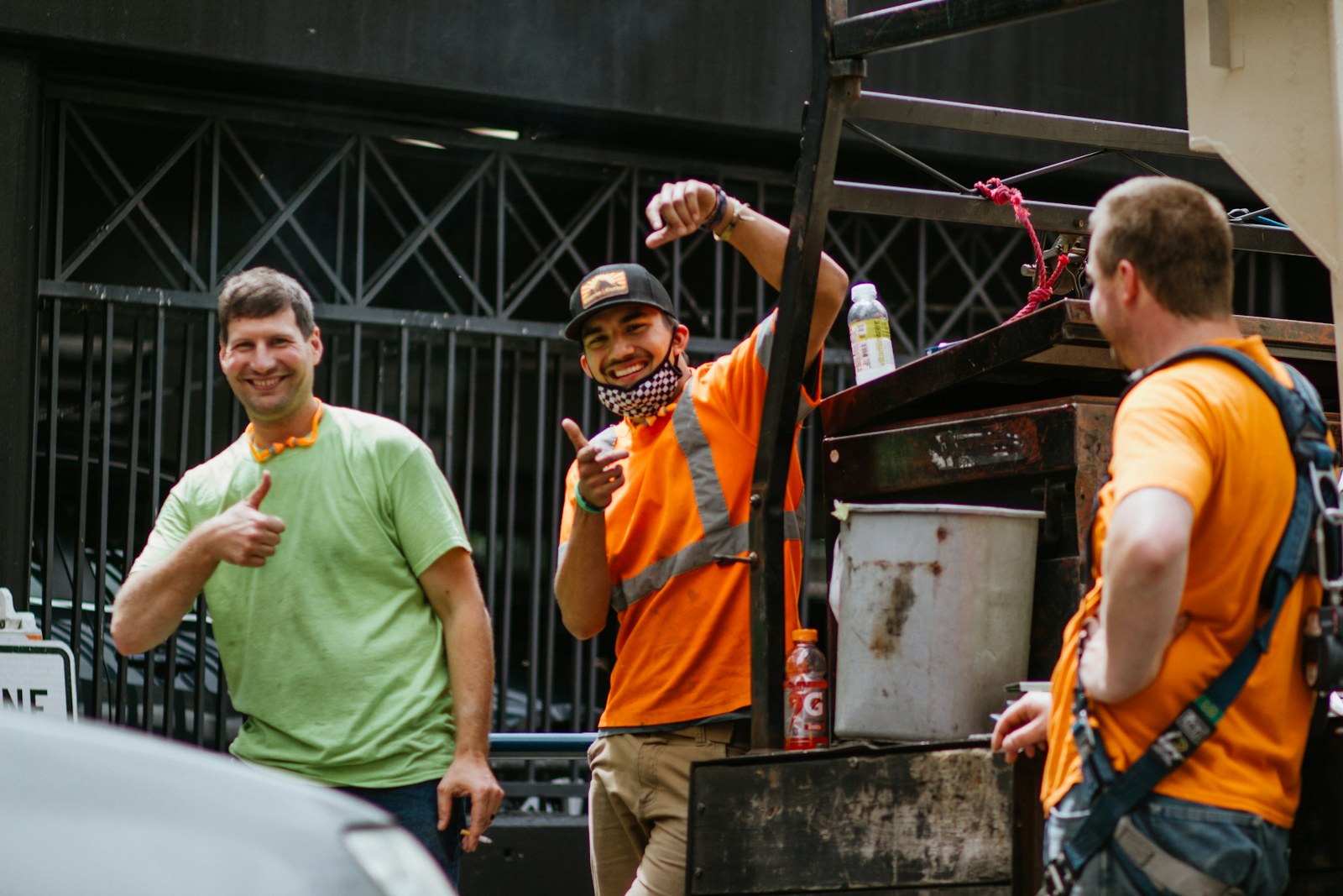 man in green crew neck t-shirt holding orange and yellow plastic cups