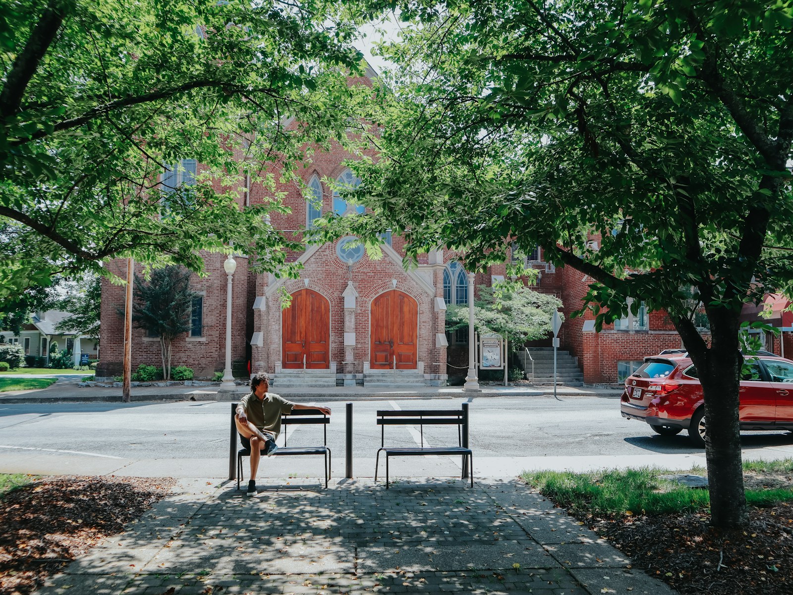 Person sits on a bench in front of a church