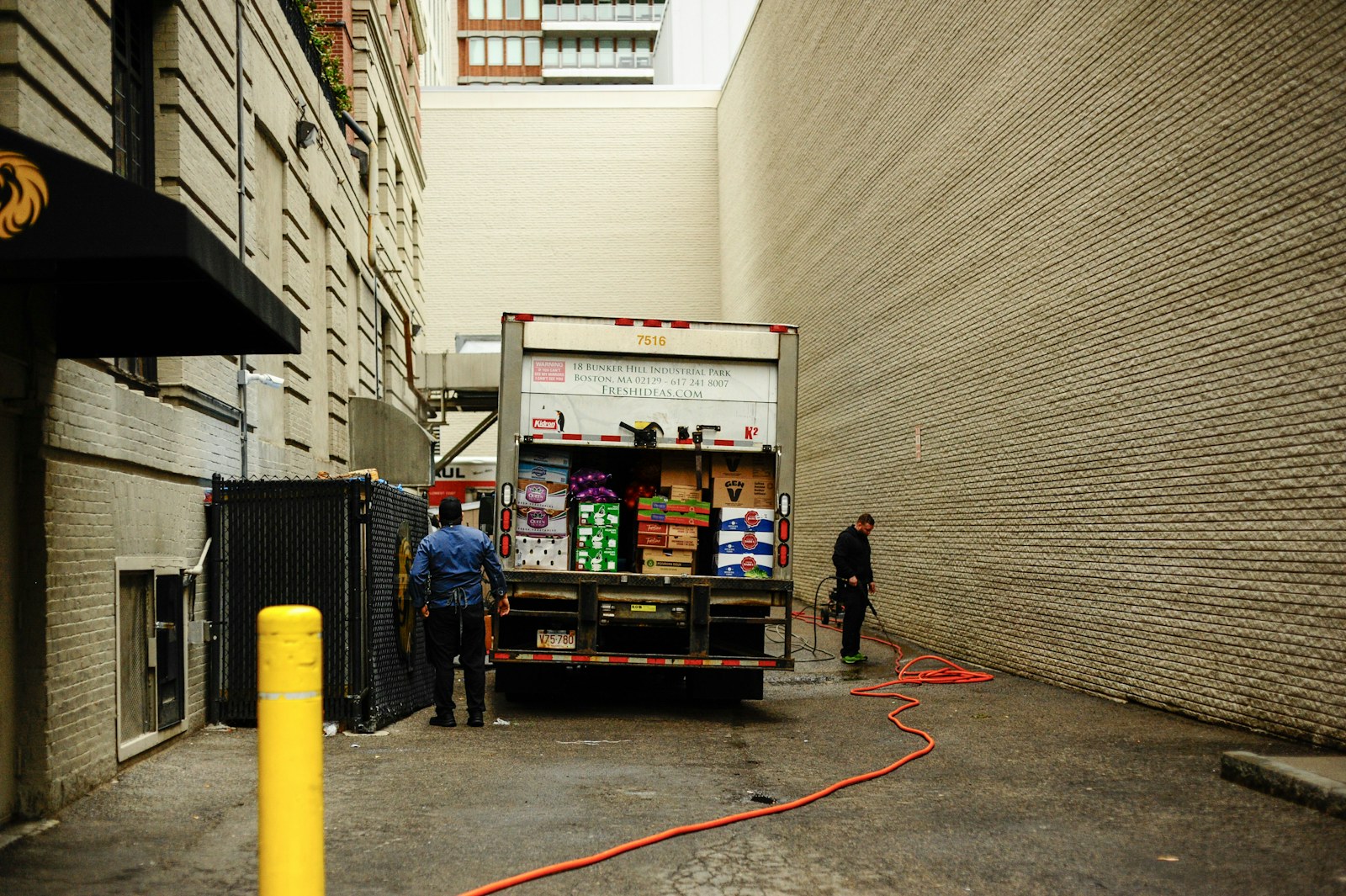 Two men unloading a delivery truck in an alley