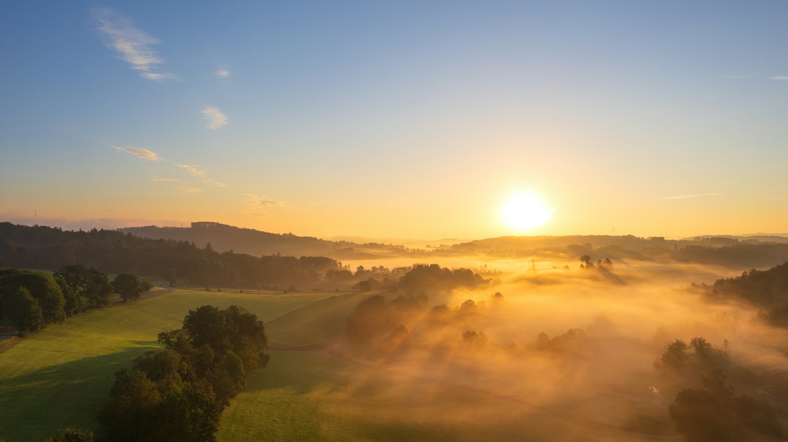 The sun is setting over a foggy valley
