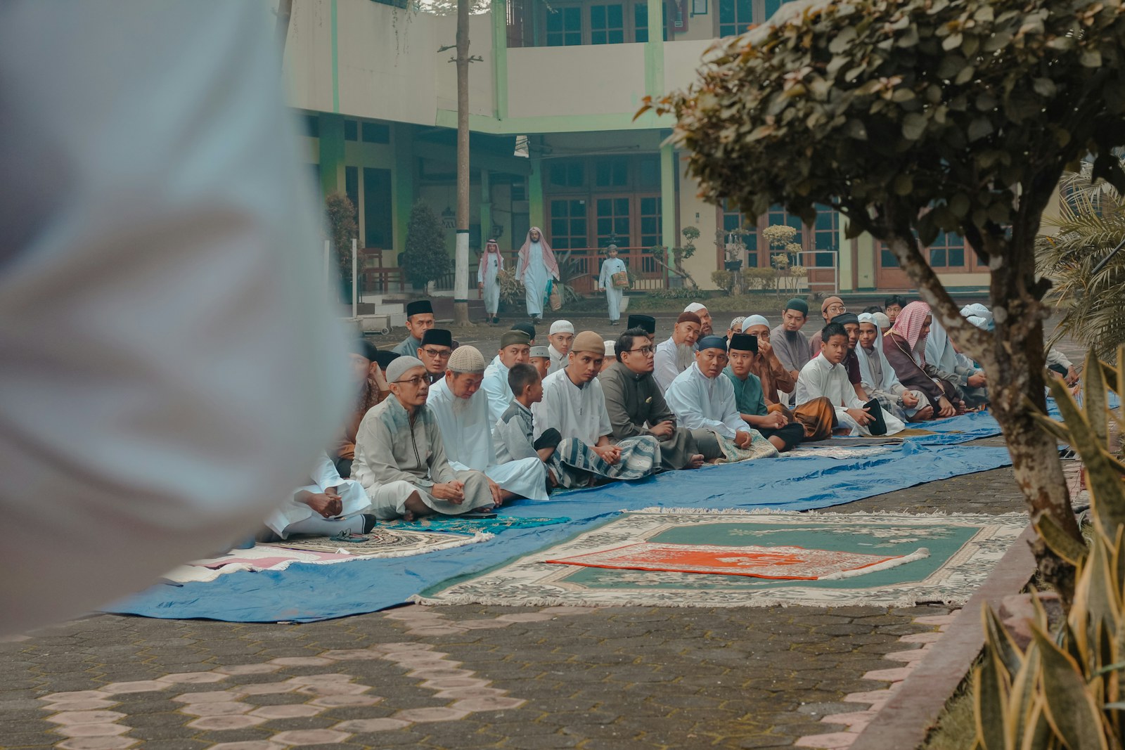 A group of men sitting on prayer mats outdoors