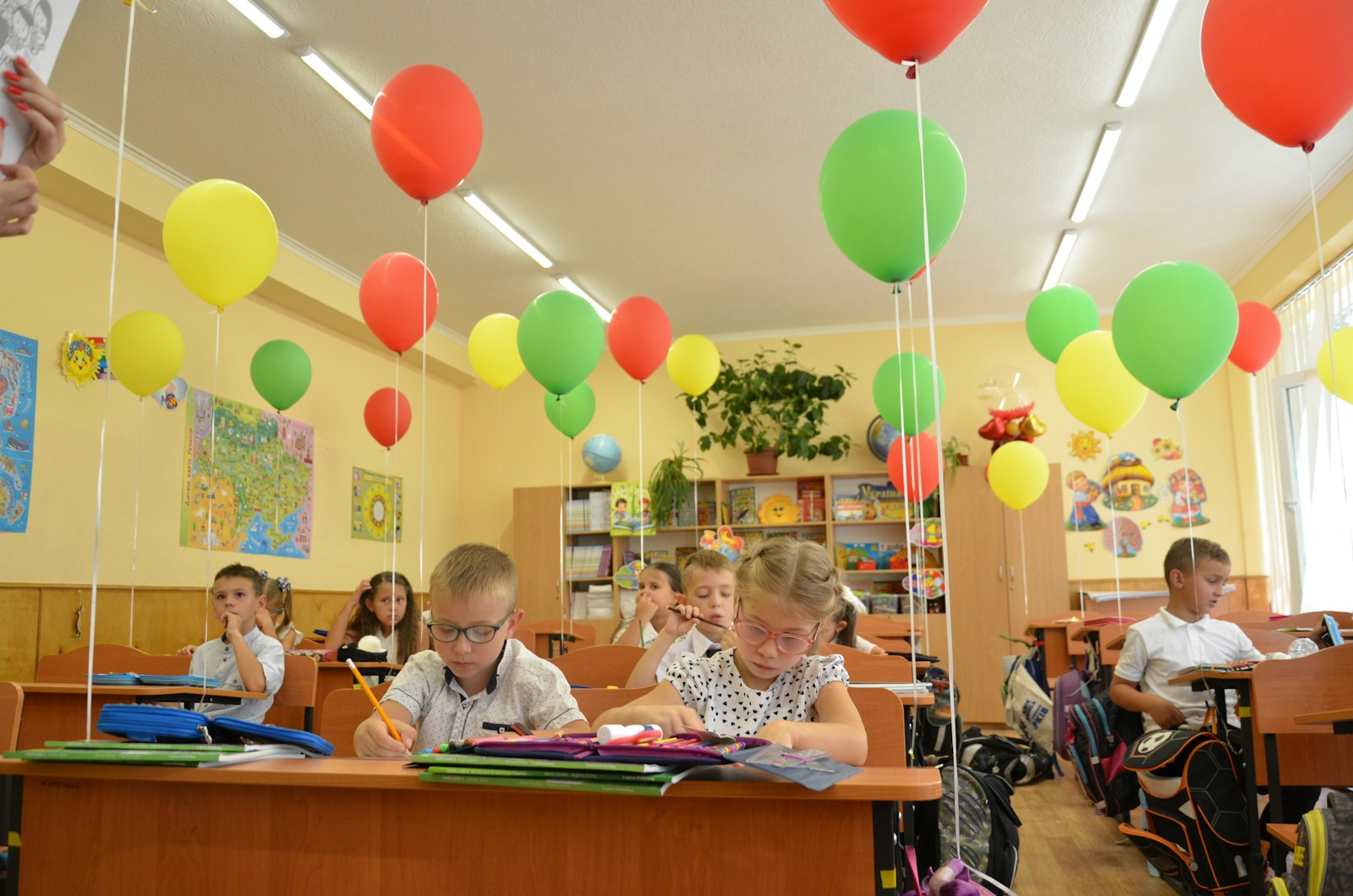Children learning in a classroom decorated with colorful balloons