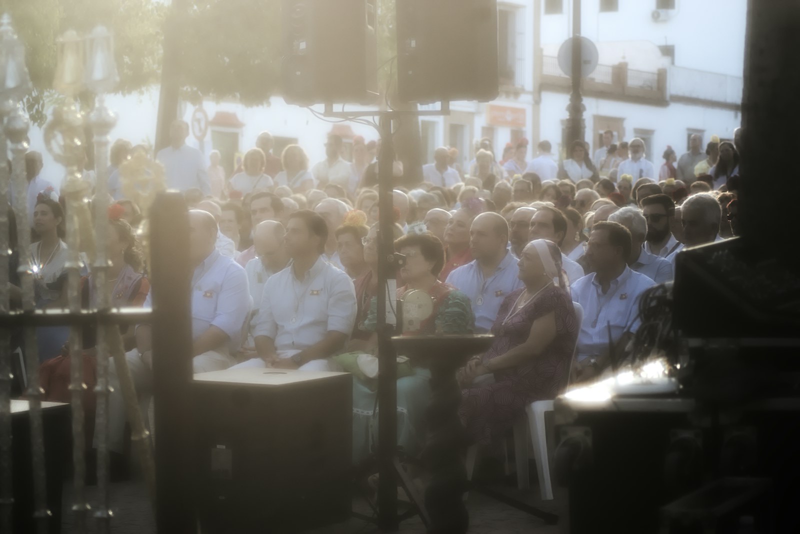 A crowd of people sitting in chairs at an outdoor event in warm light