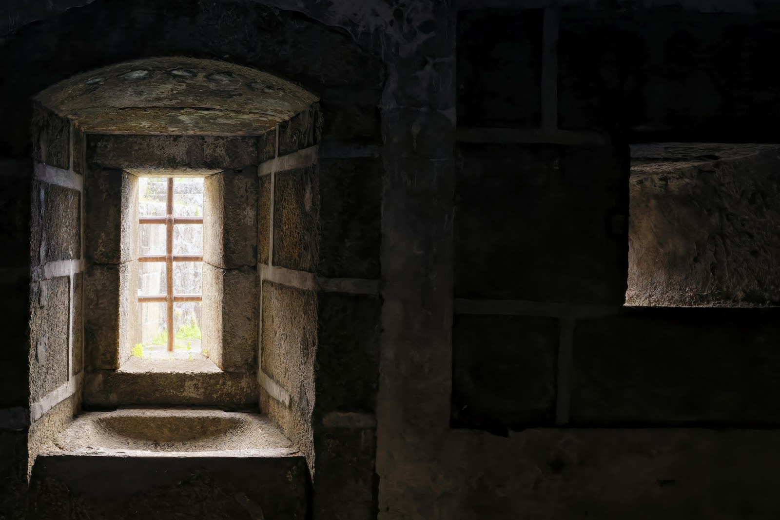 a window in a stone building with a light coming through