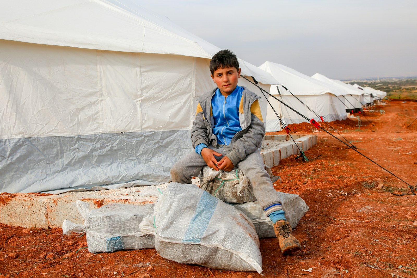 A young boy sitting outside of a tent