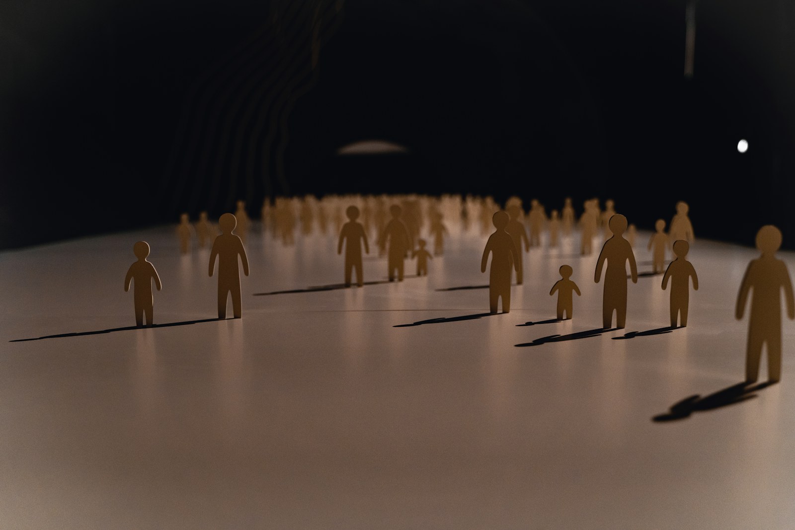 A group of small paper cutout figures on a white surface with long shadows