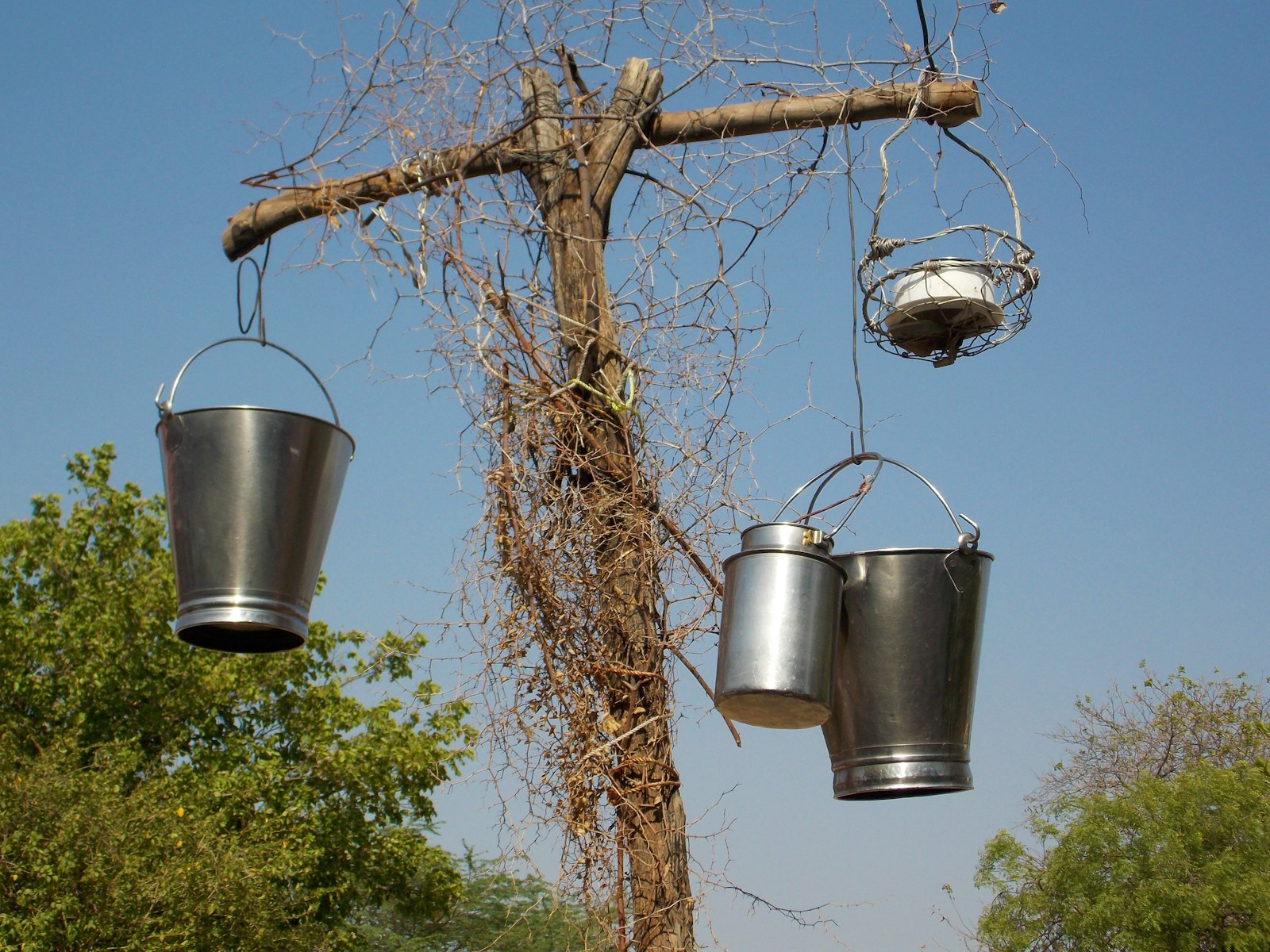 Metal buckets hanging from a wooden post outdoors