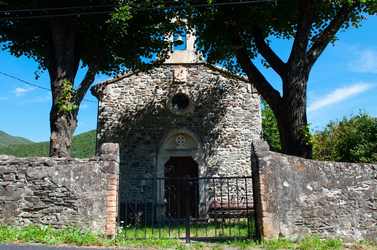 a stone church surrounded by trees and a fence