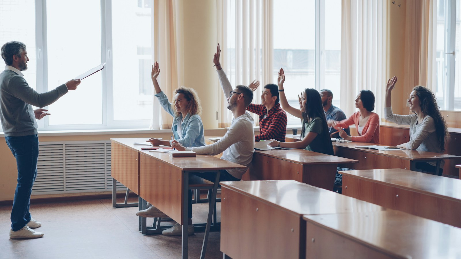 Teacher pointing at students with raised hands