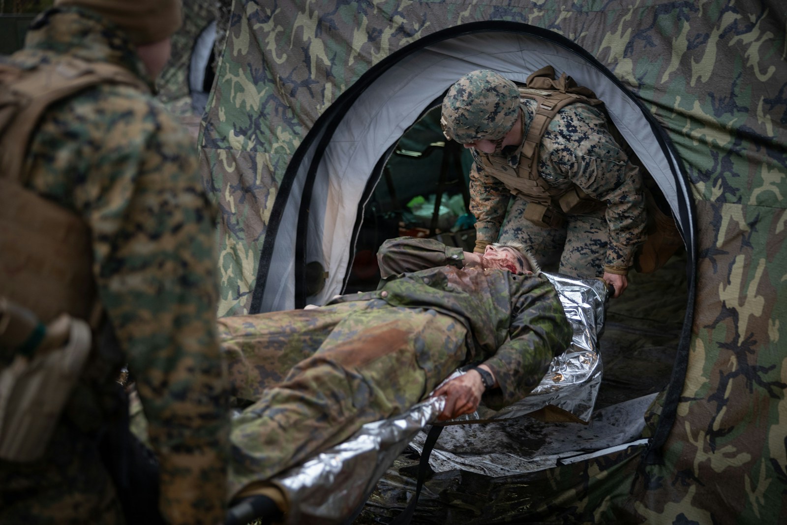 Marines assist injured soldier in a tent