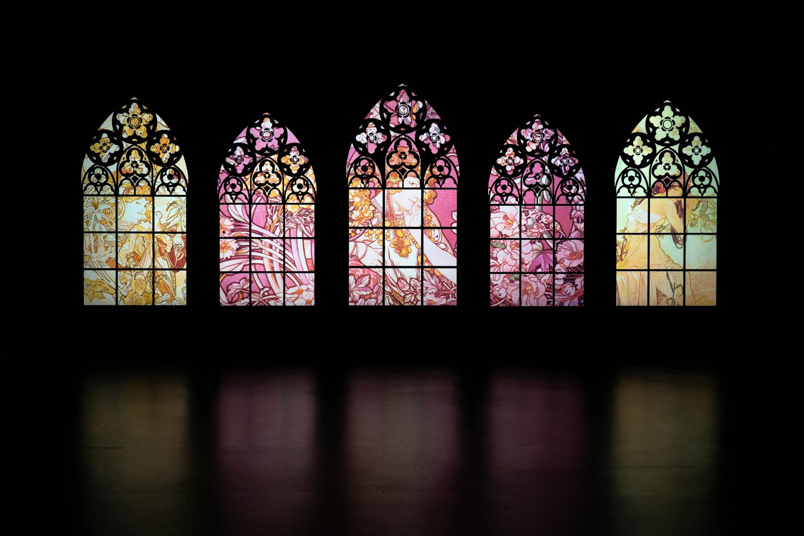 a set of four stained glass windows in a dark room