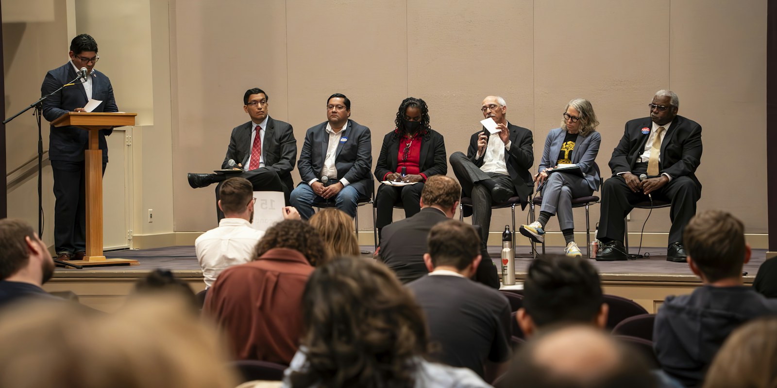 A group of people sitting on a stage in front of a crowd