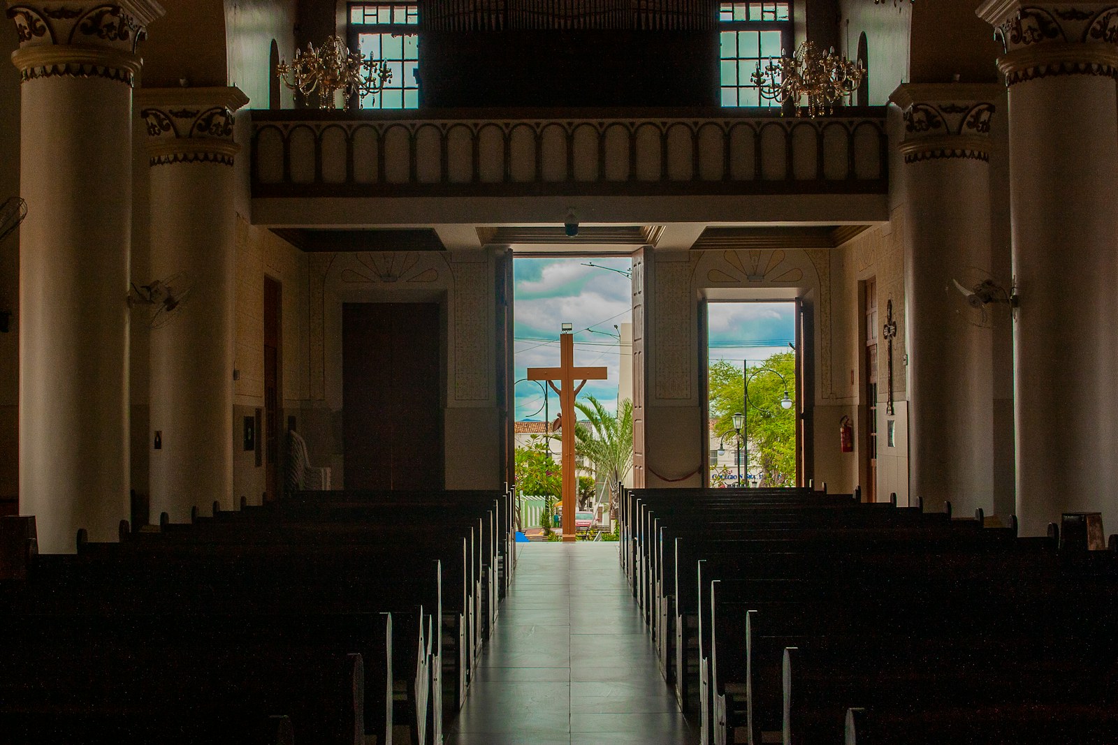 Empty church pews lead to a cross in the distance