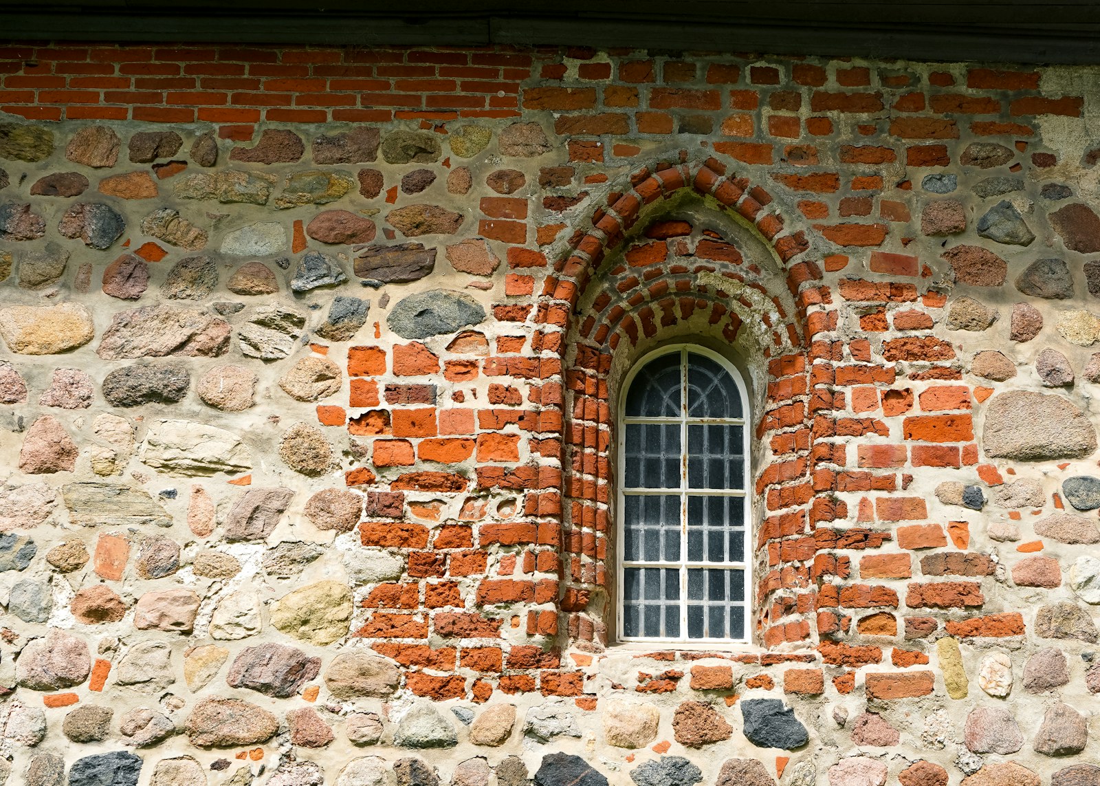 An old stone and brick wall with an arched window