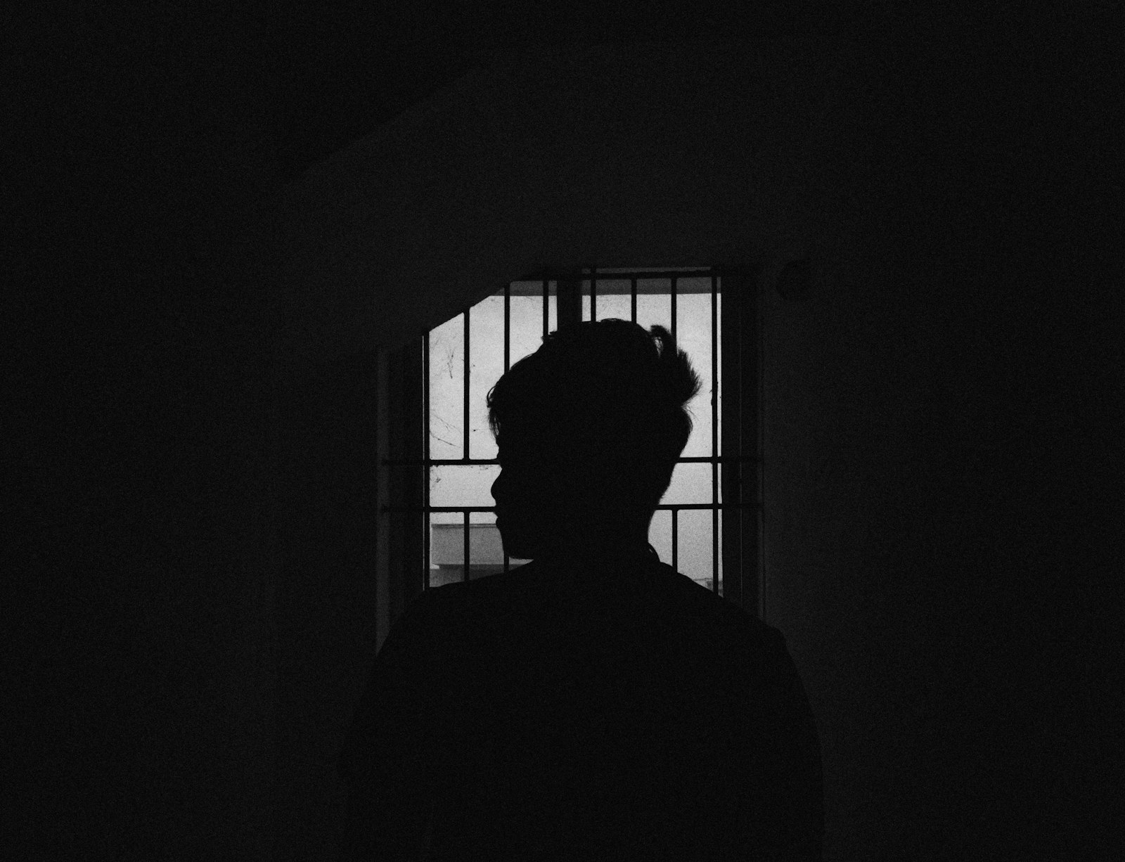 a person standing in front of a window in a dark room