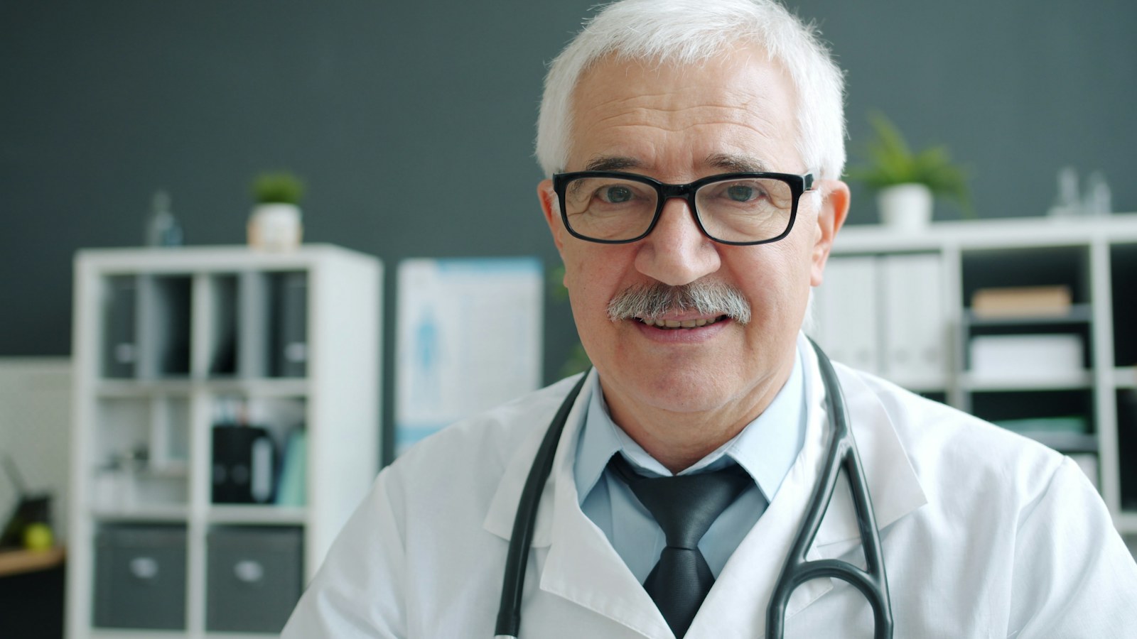 Elderly doctor wearing glasses and stethoscope in office
