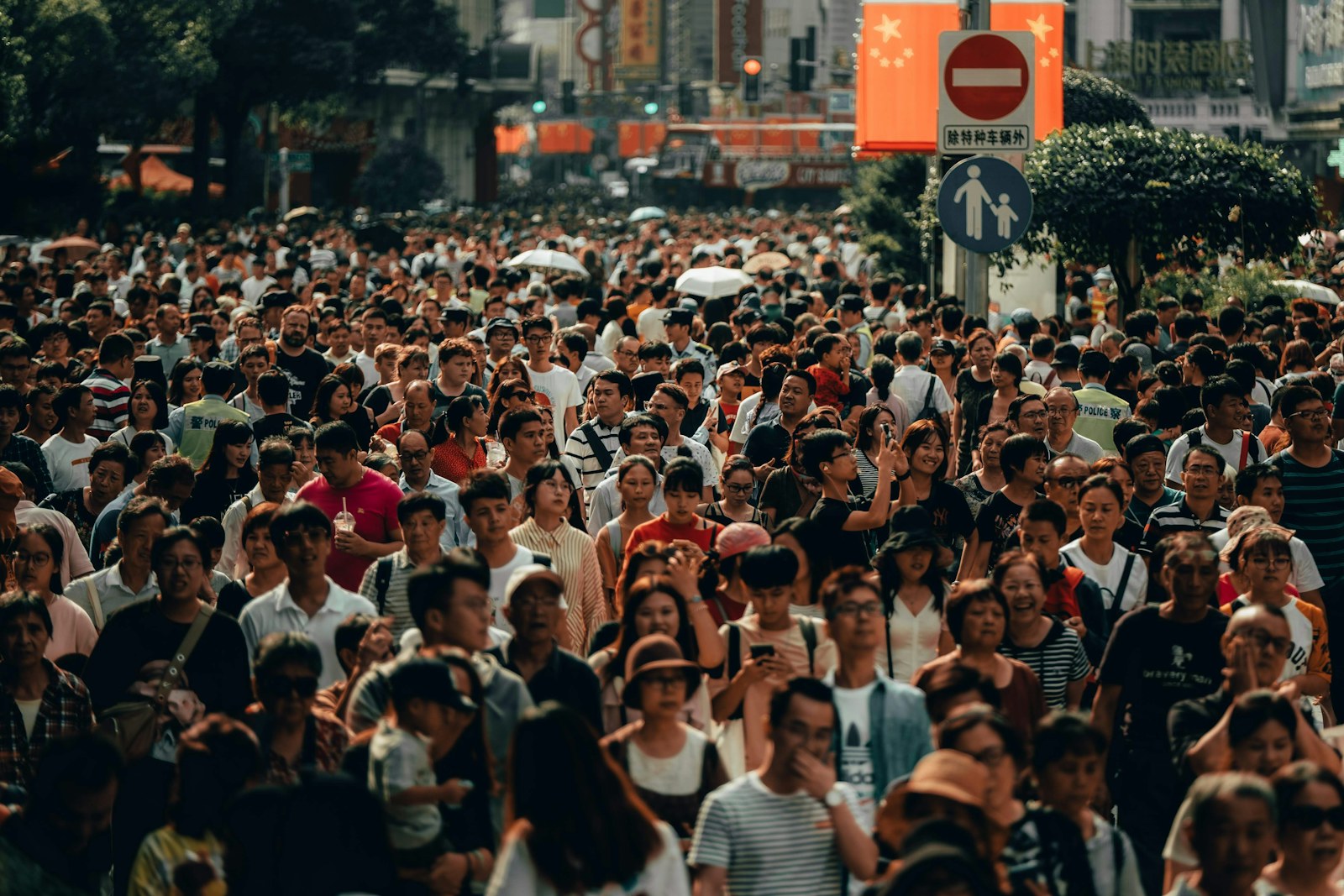 A dense crowd of people walking along a busy city street