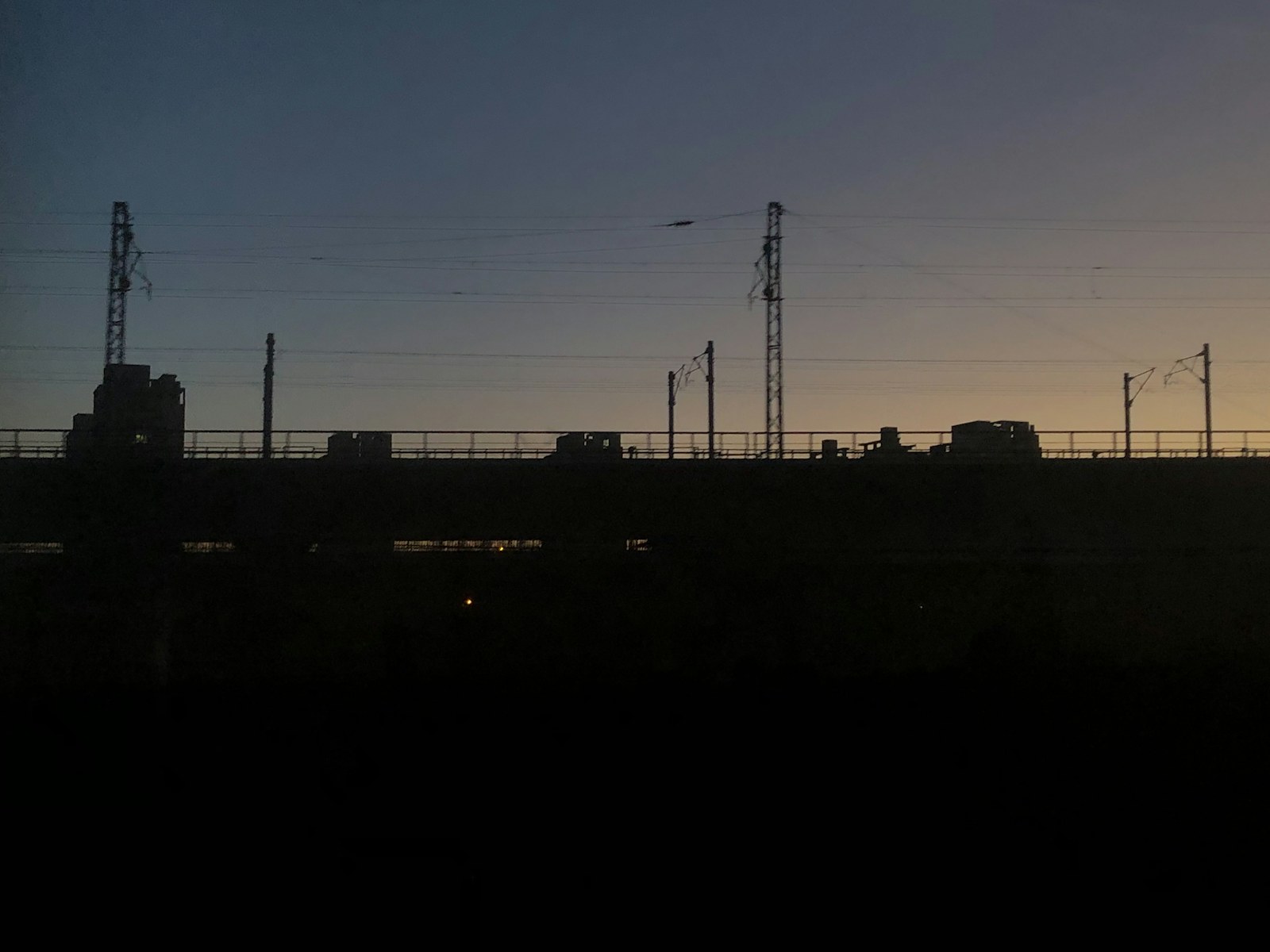 The sun is setting behind a fence with a city in the background