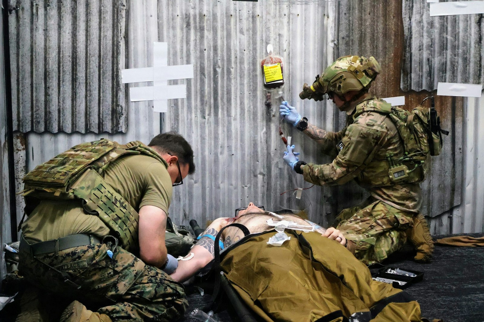 Two military medics treat an injured person with an iv
