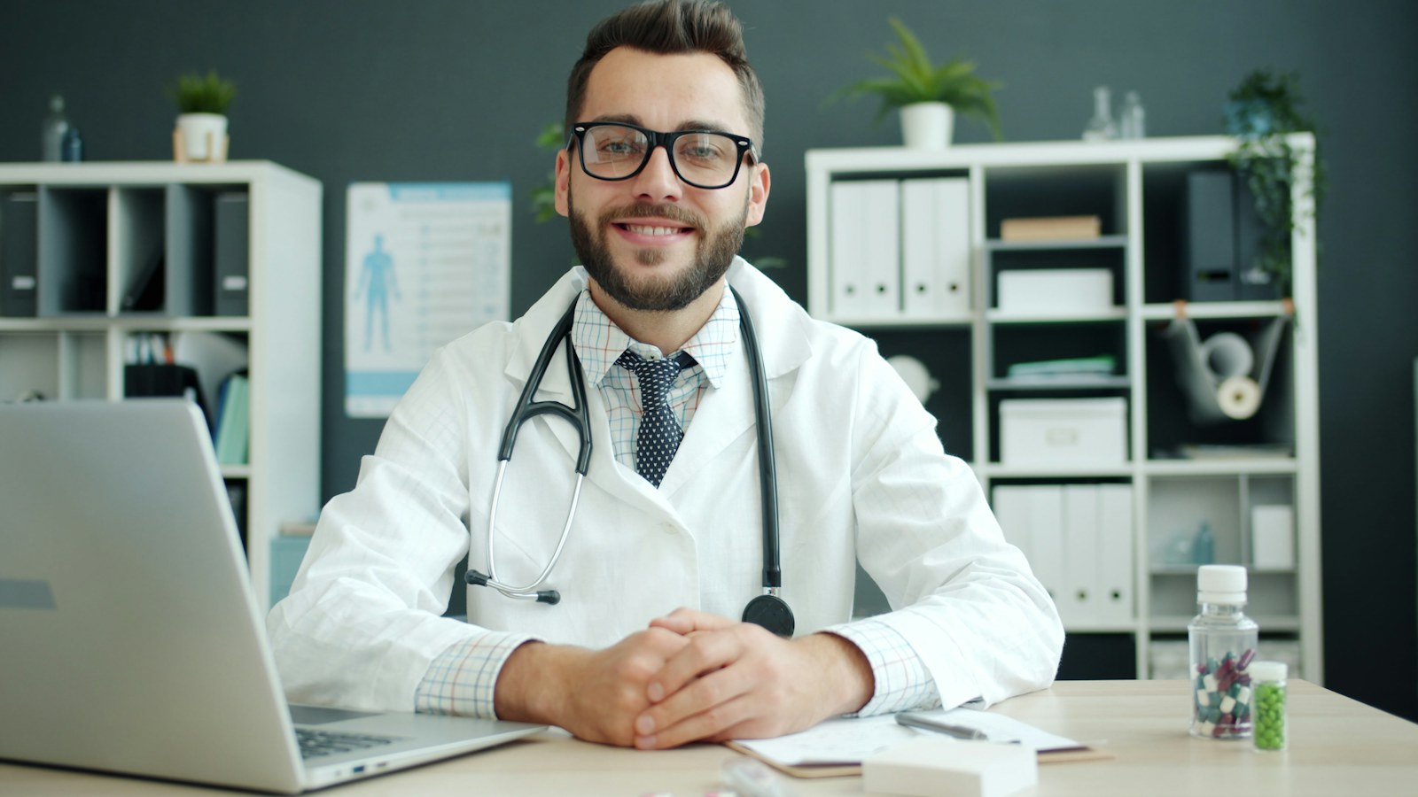 Doctor wearing a stethoscope sits at a desk