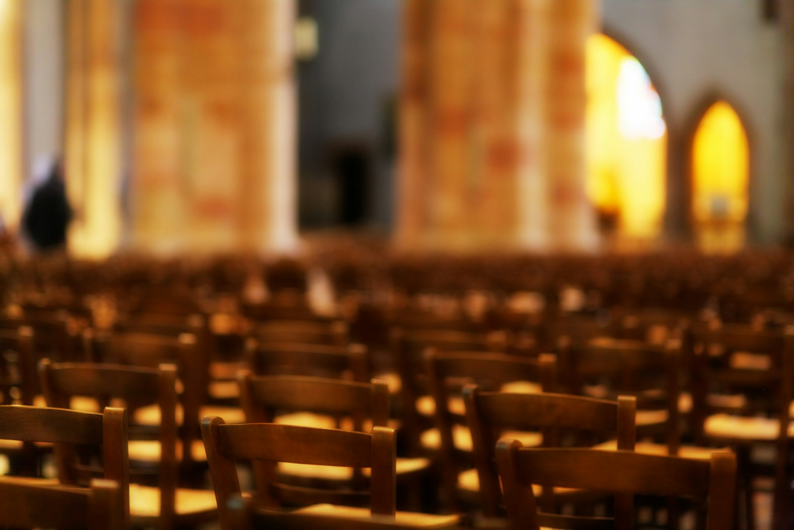 Rows of empty wooden chairs in a large hall