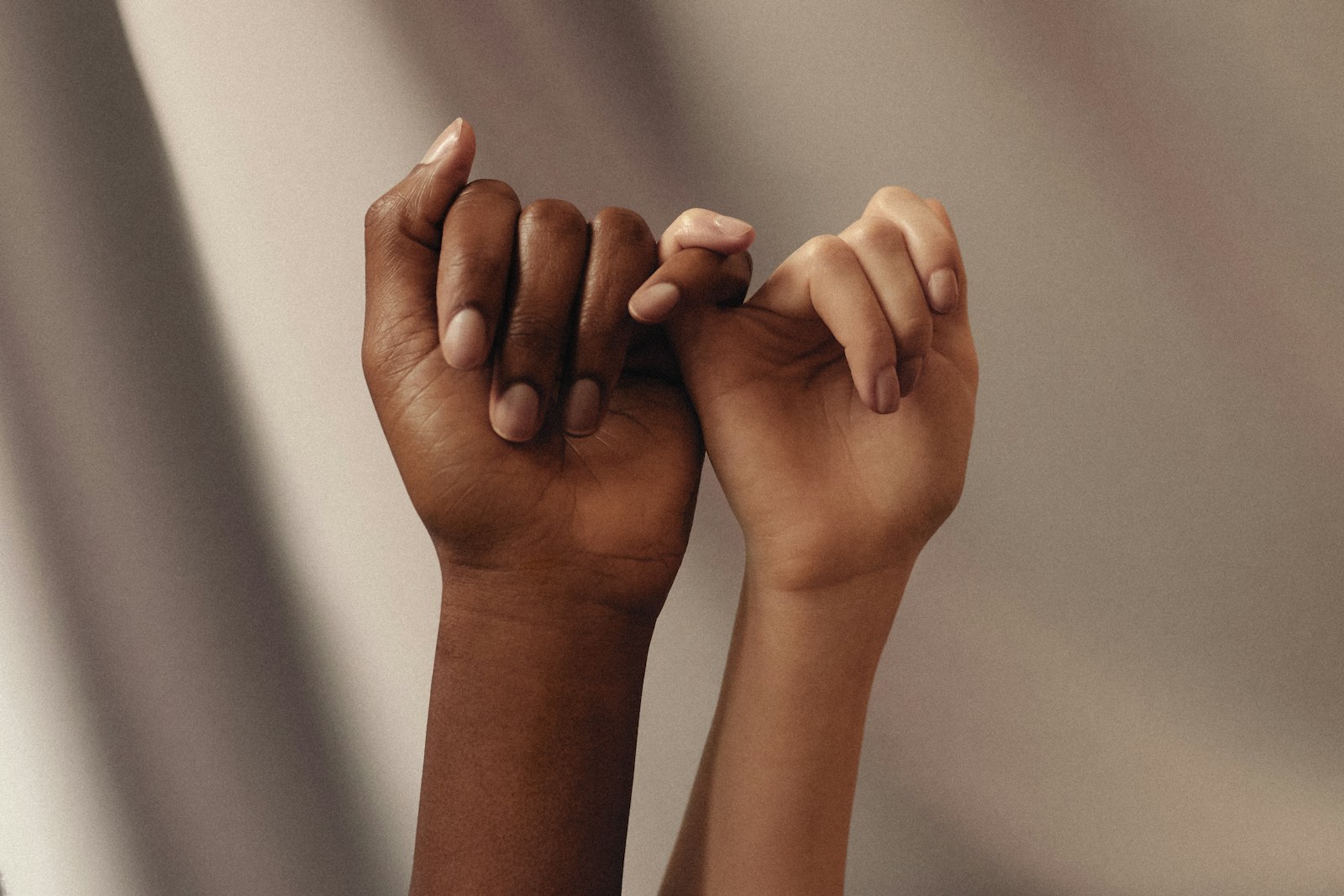 two hands with linked pinky fingers